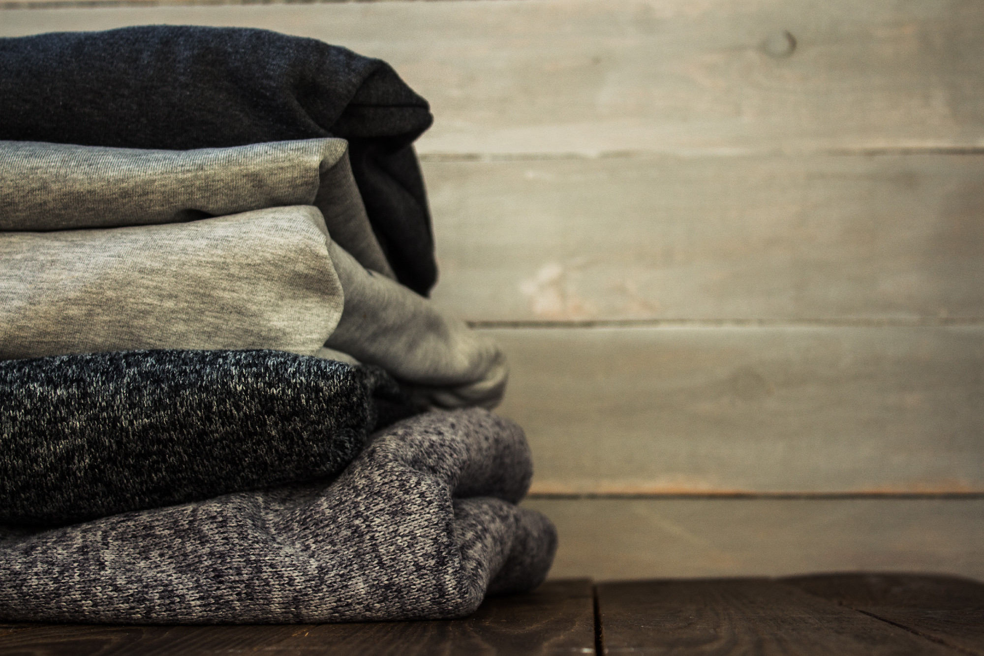 a stack of sweter on a wooden background