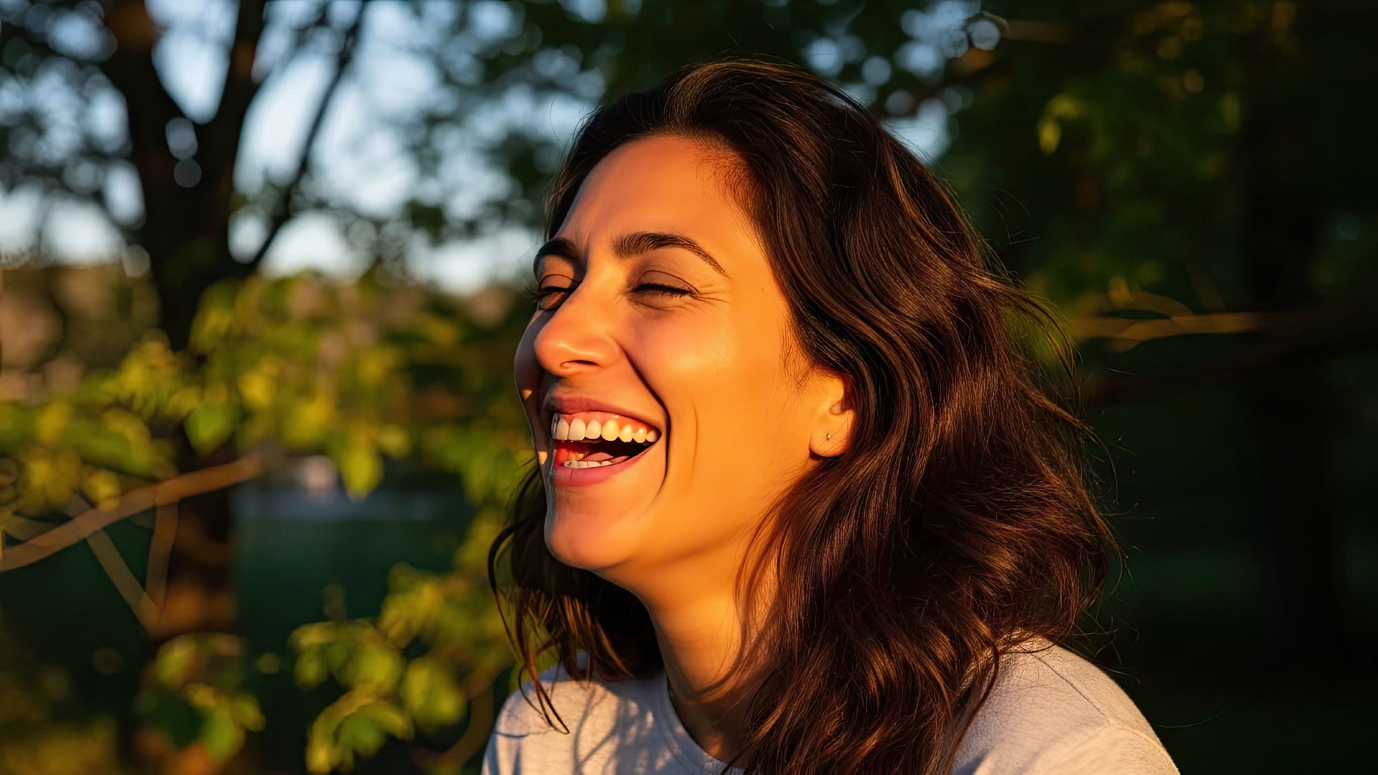 Woman laughing joyfully with sunlight illuminating her face outd
