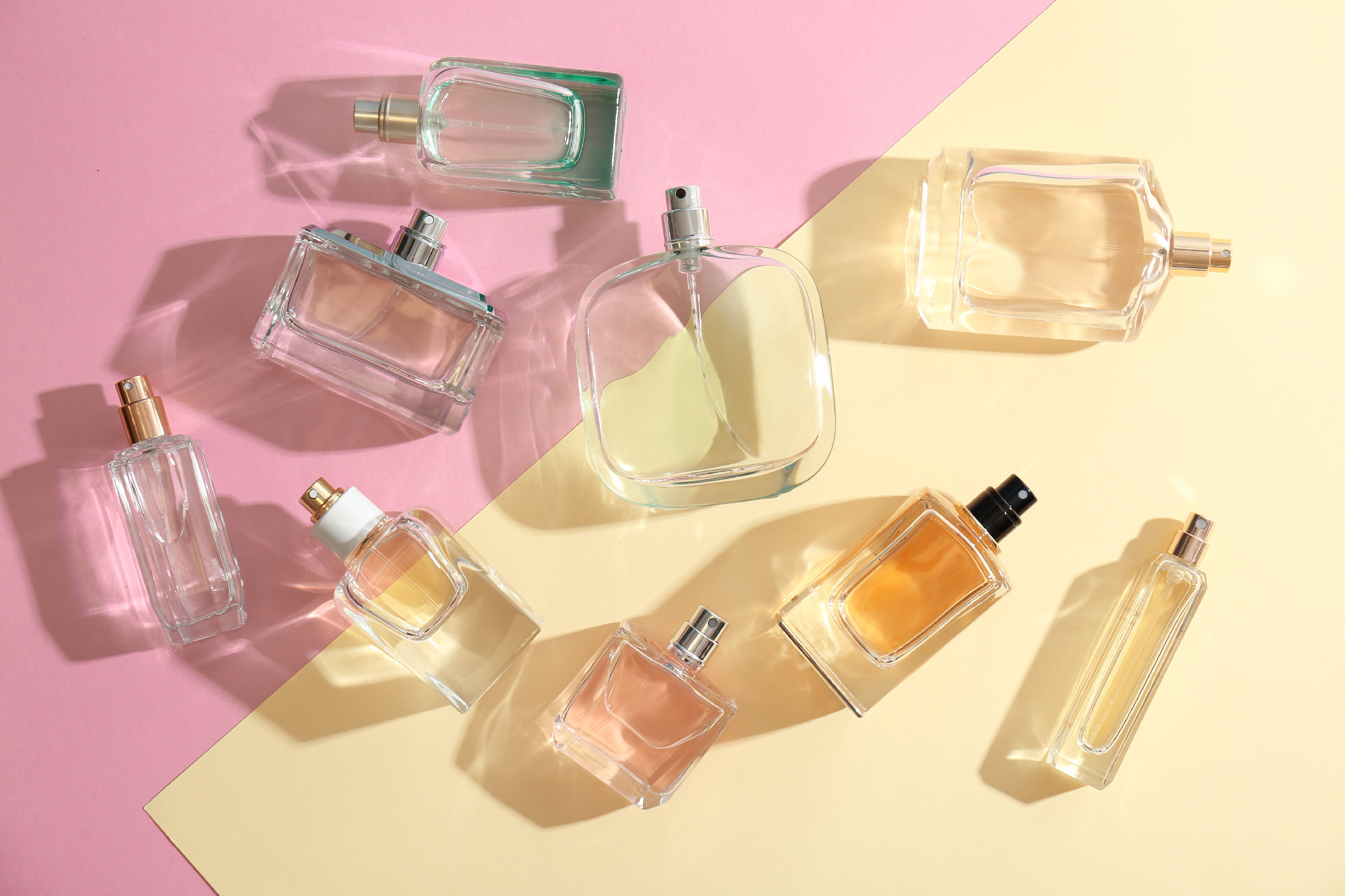 Perfume bottles on colorful background, flat lay�