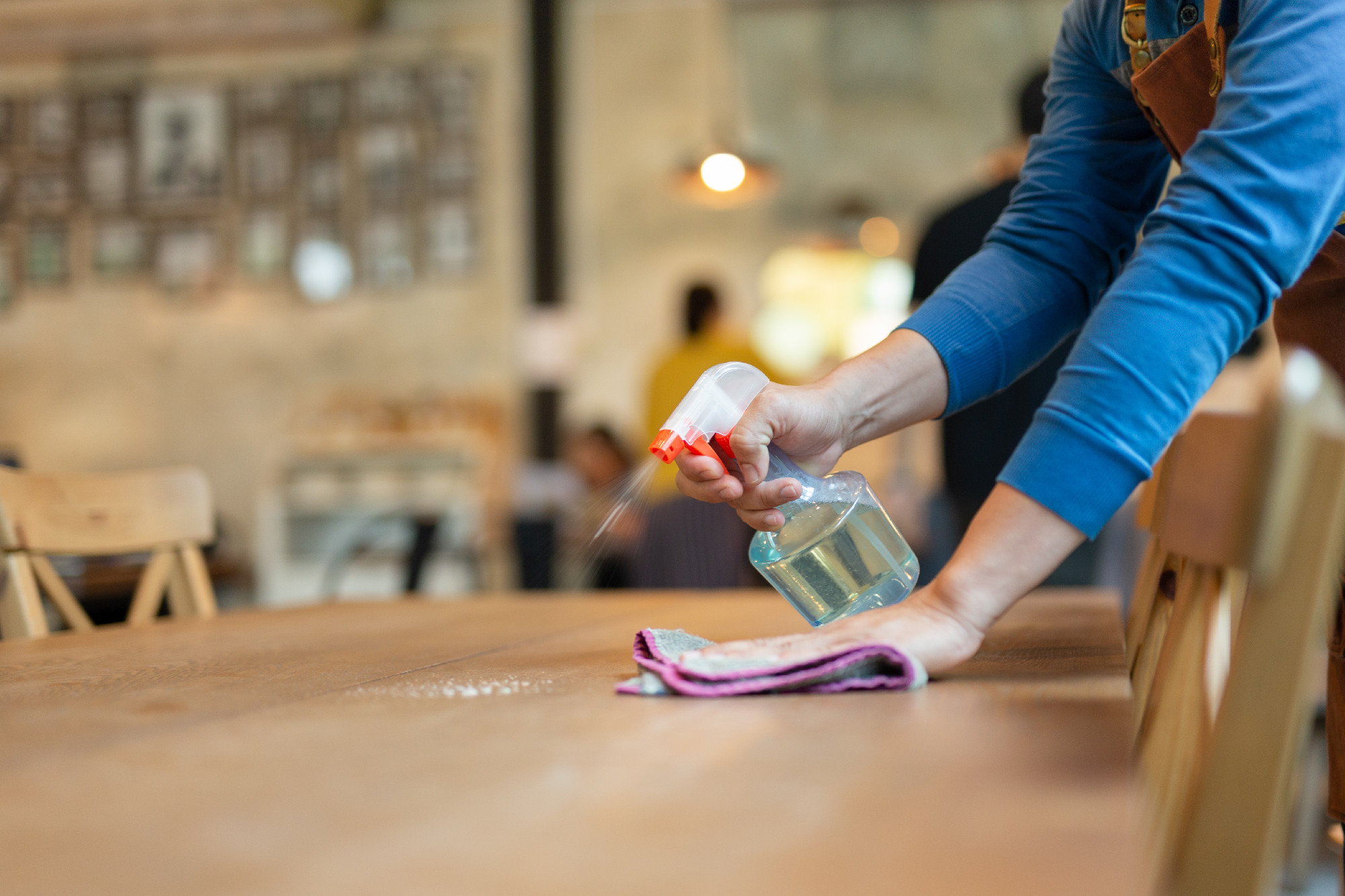 Waiter cleaning the table with spray disinfectant on table in restaurant.