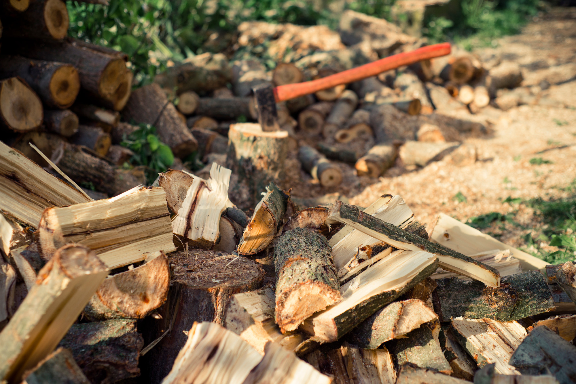 Axe stuck in a stump on background of chopped firewood