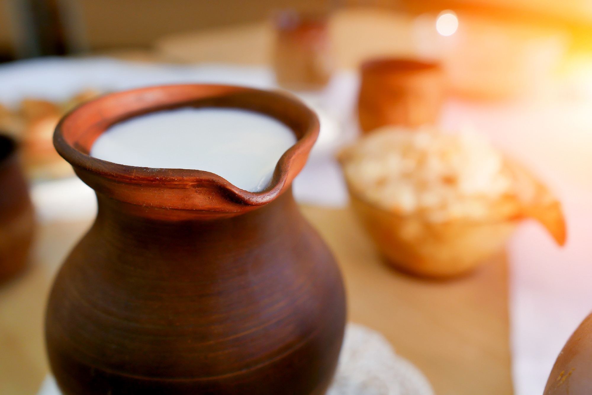 clay jug of milk on the table . Organic food
