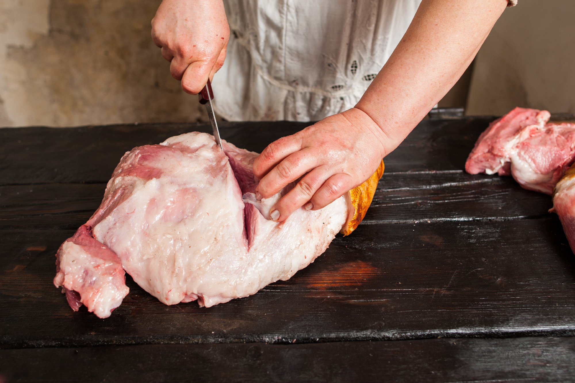 Slicing raw pork meat in farm market