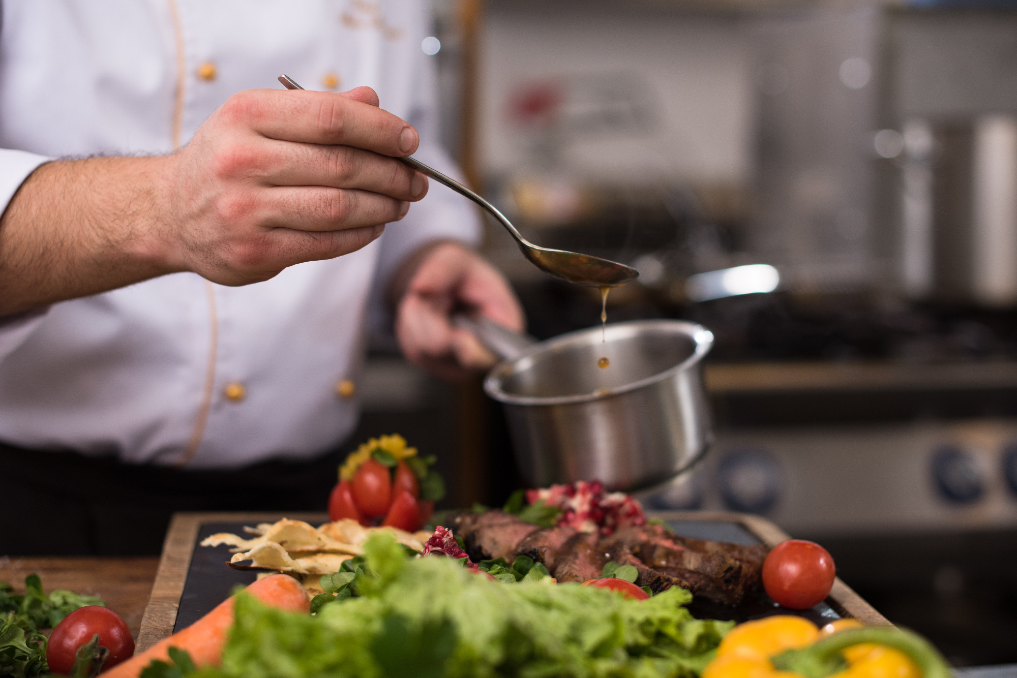 Chef hand finishing steak meat plate