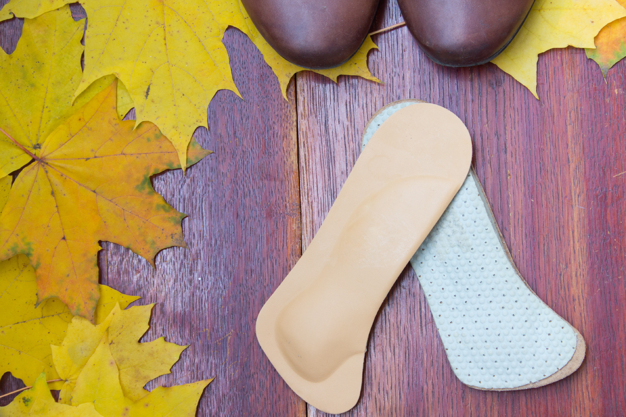 Brown shoes with orthopedic insoles. Autumnal background, maple