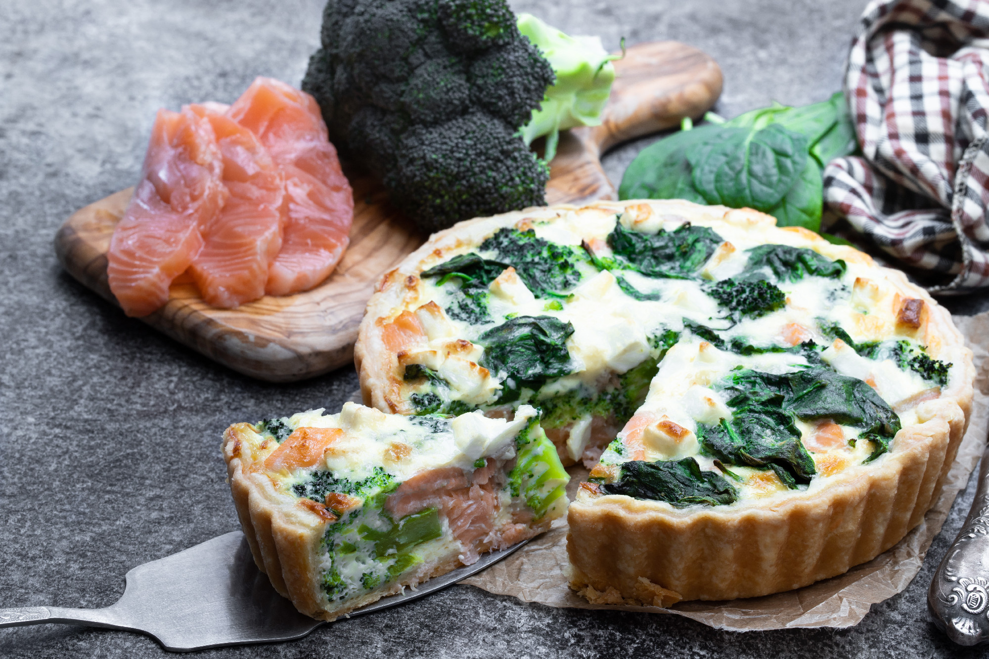 Raw salmon quiche wich broccoli and spinach on gray table