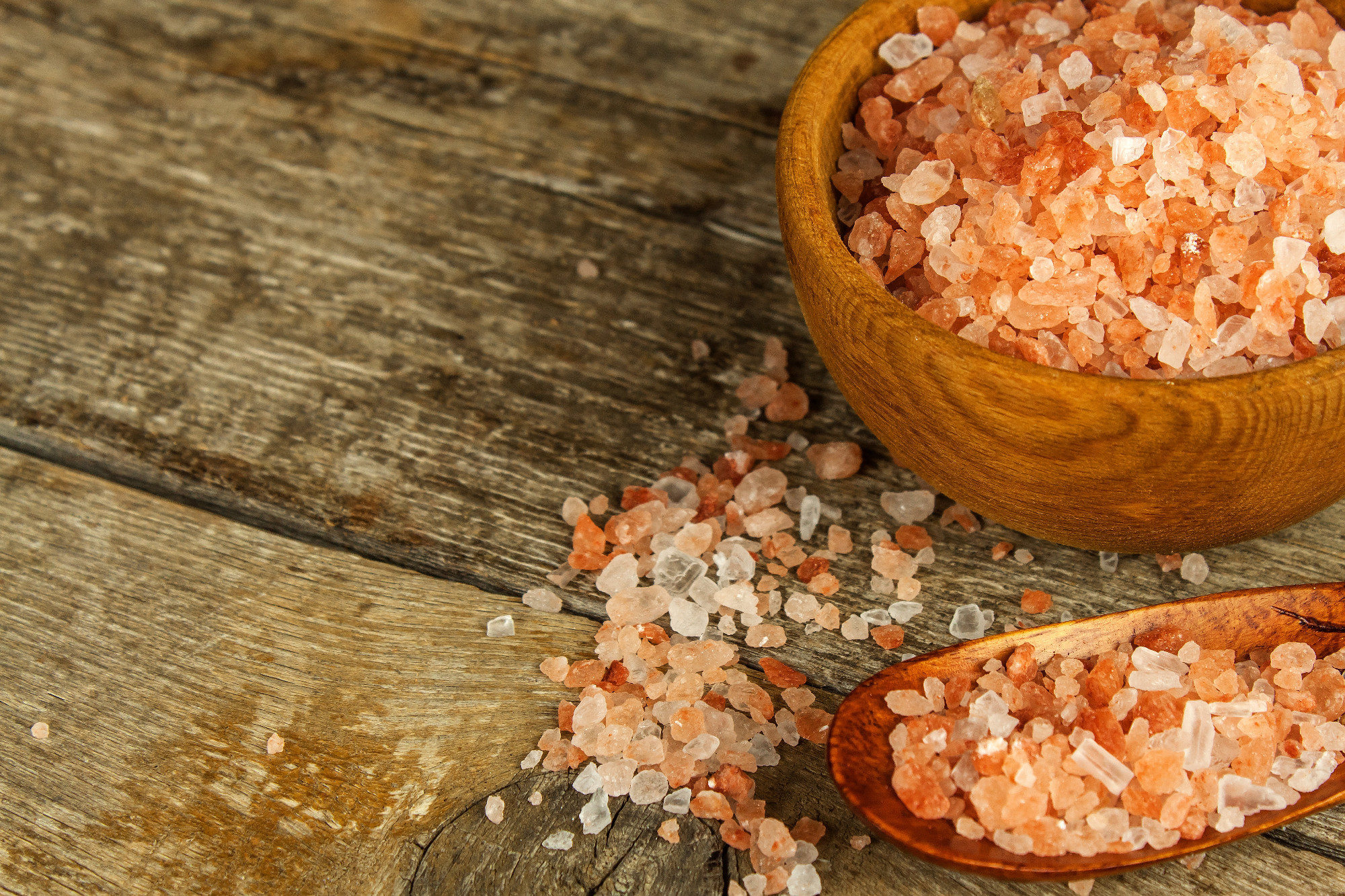 Pink salt from the Himalayas on wooden background. Pile of pink Himalayan salt. Sale of spices