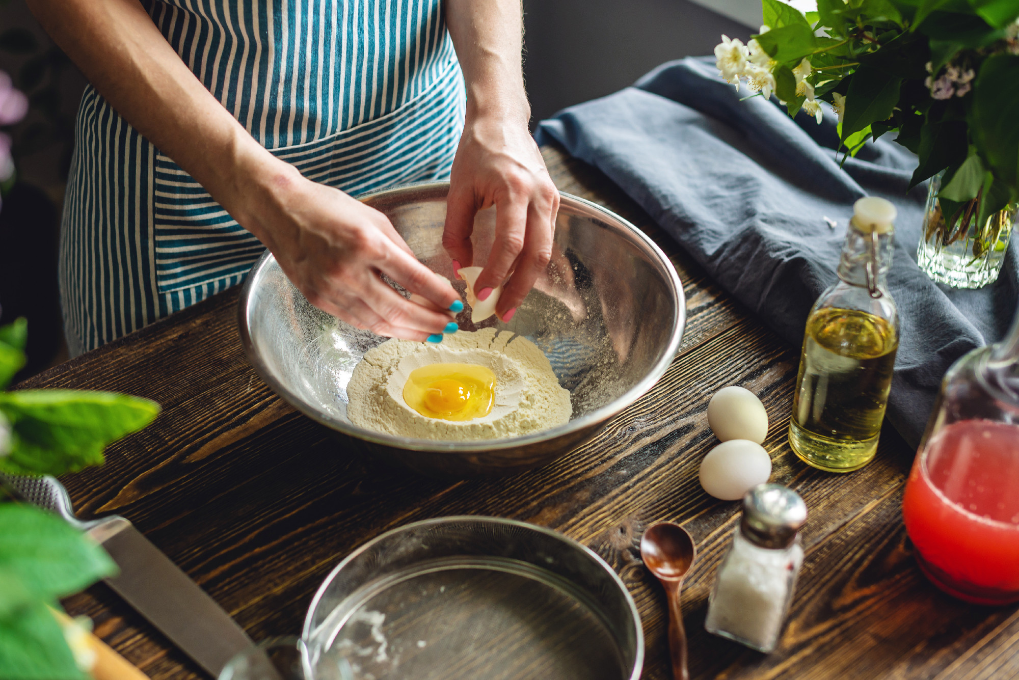 A woman is breaking an egg to make dough. Making handmade pasta in a pleasant and cozy home environment