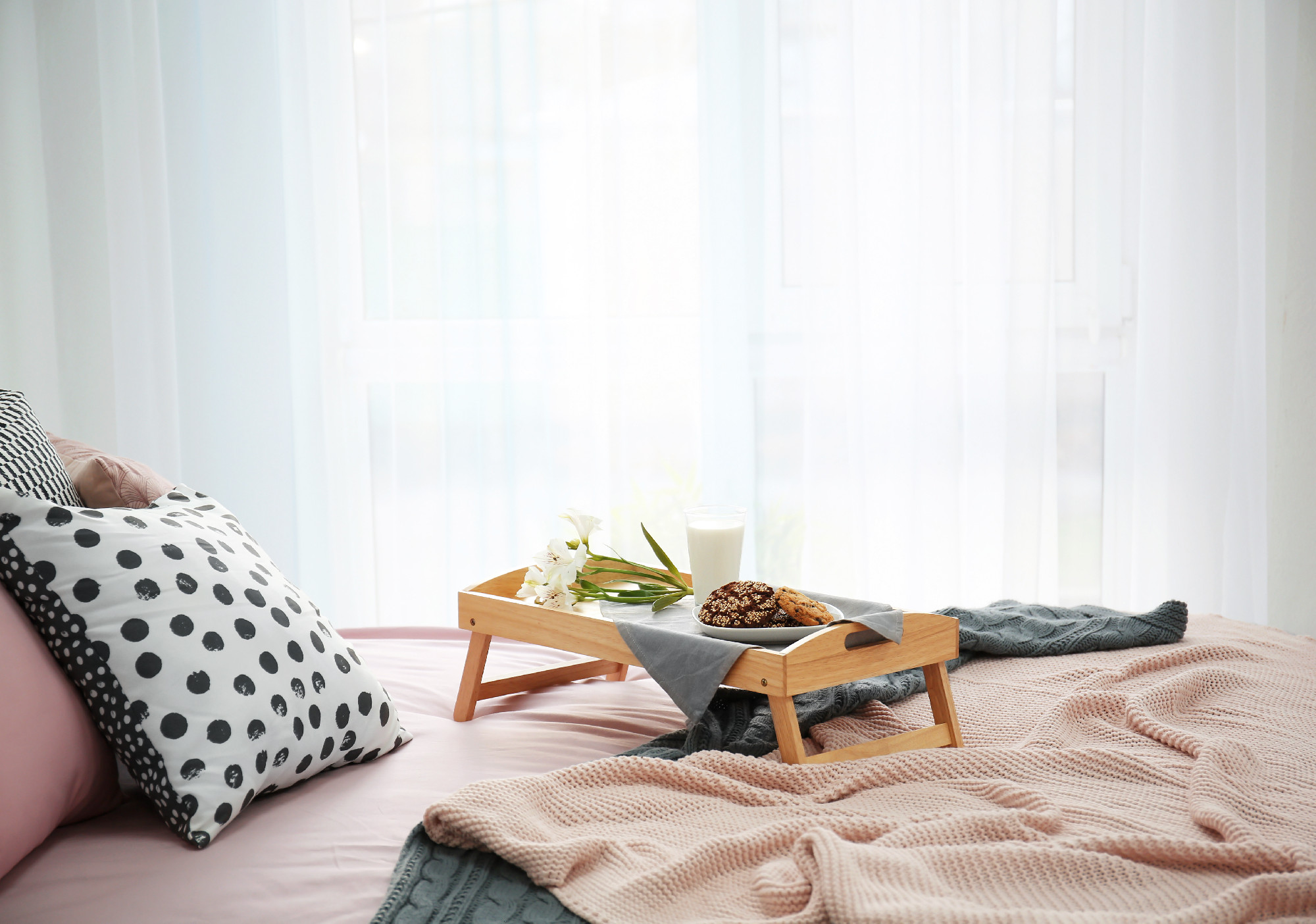 Tray with tasty breakfast and flowers on bed�