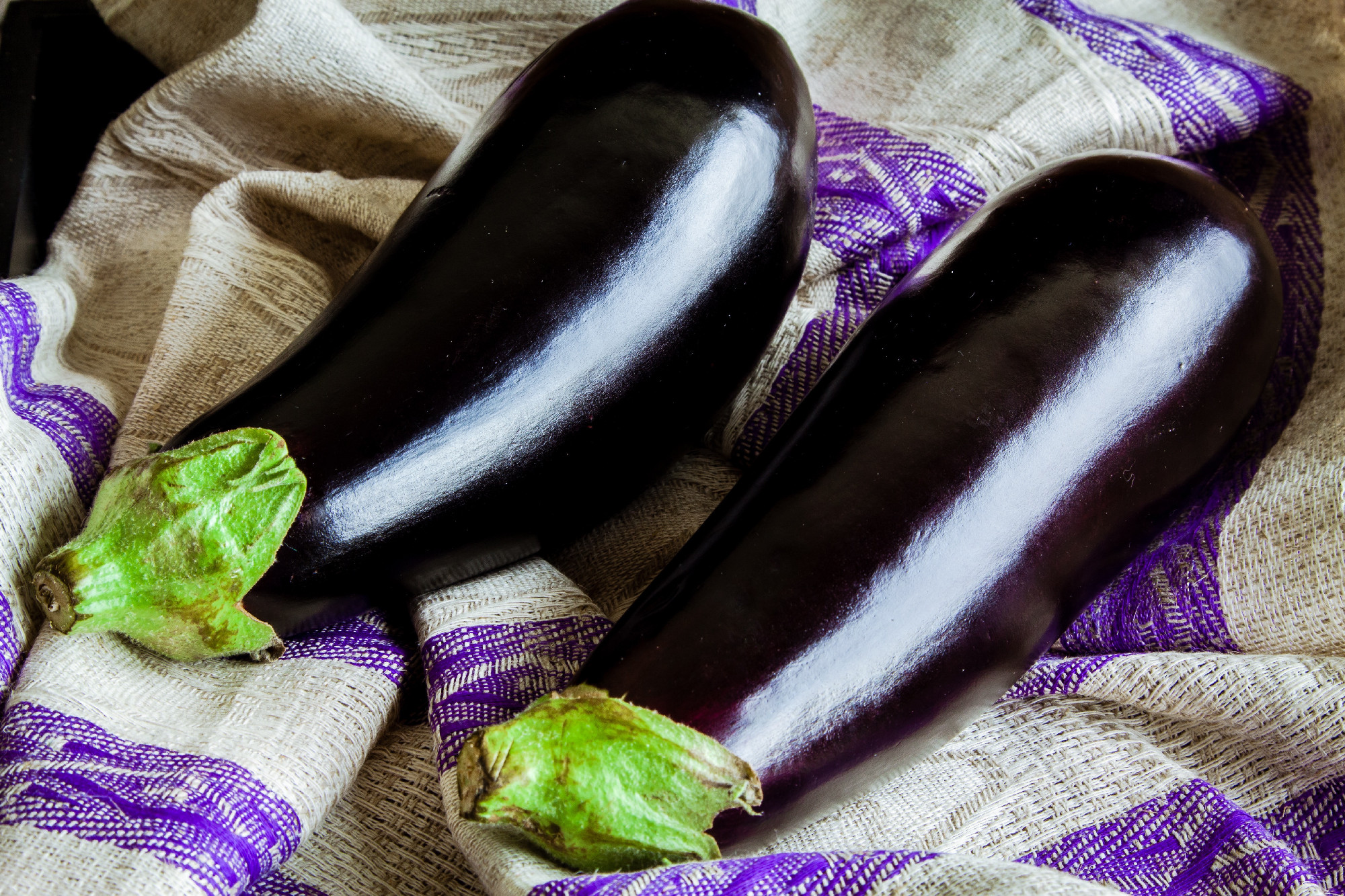 two raw organic eggplant on sackcloth
