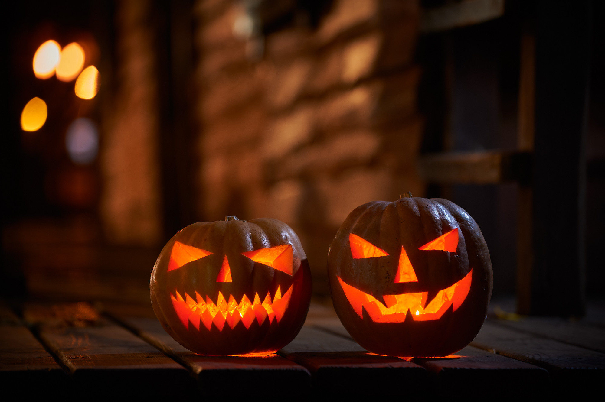 Two glowing Halloween Pumpkins at the entrance to an old wooden house