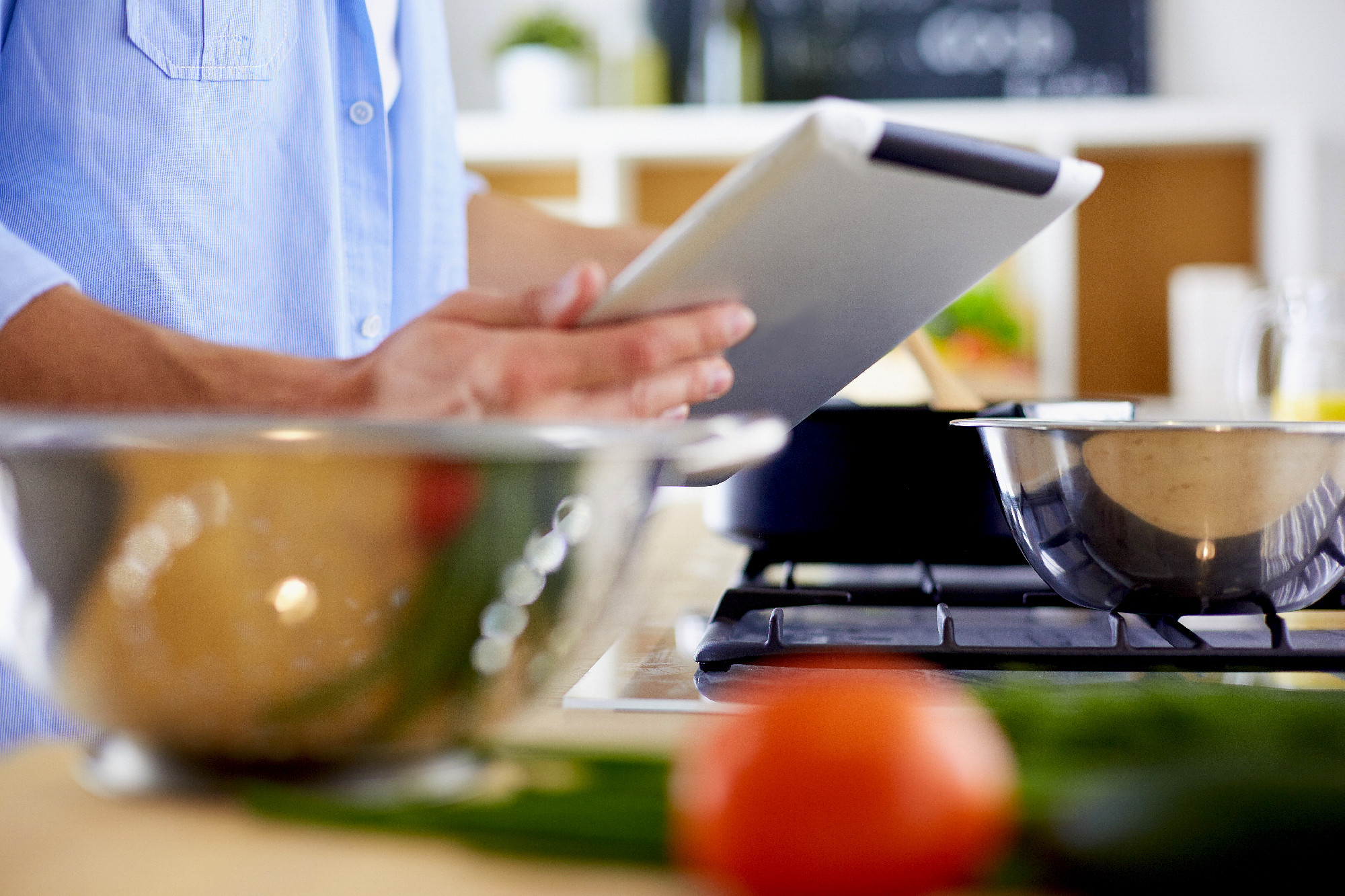 Man following recipe on digital tablet and cooking tasty and hea