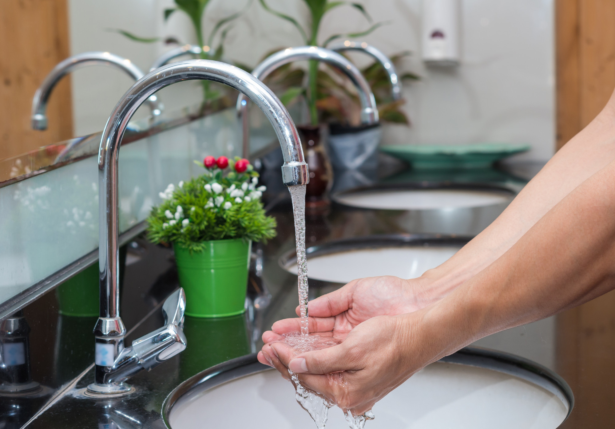 Hand washing with Chrome faucet over the washbasin in modern bat