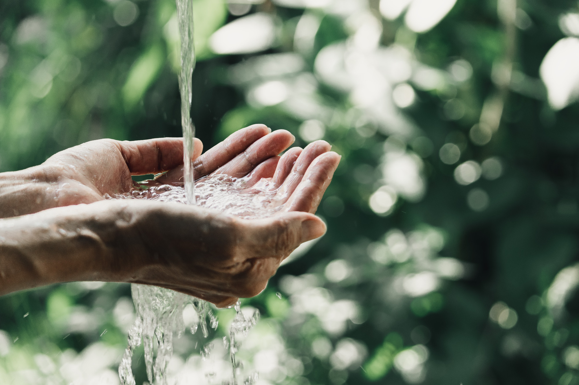 closeup water flow to hand of women for nature concept on the ga