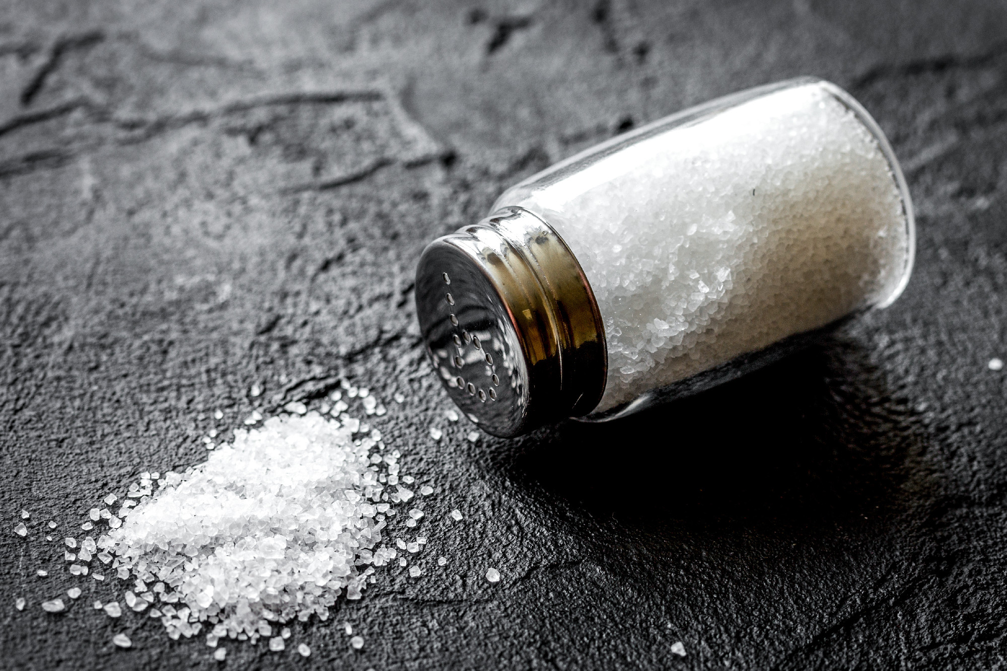 Cooking set with salt in glass bottle on dark background