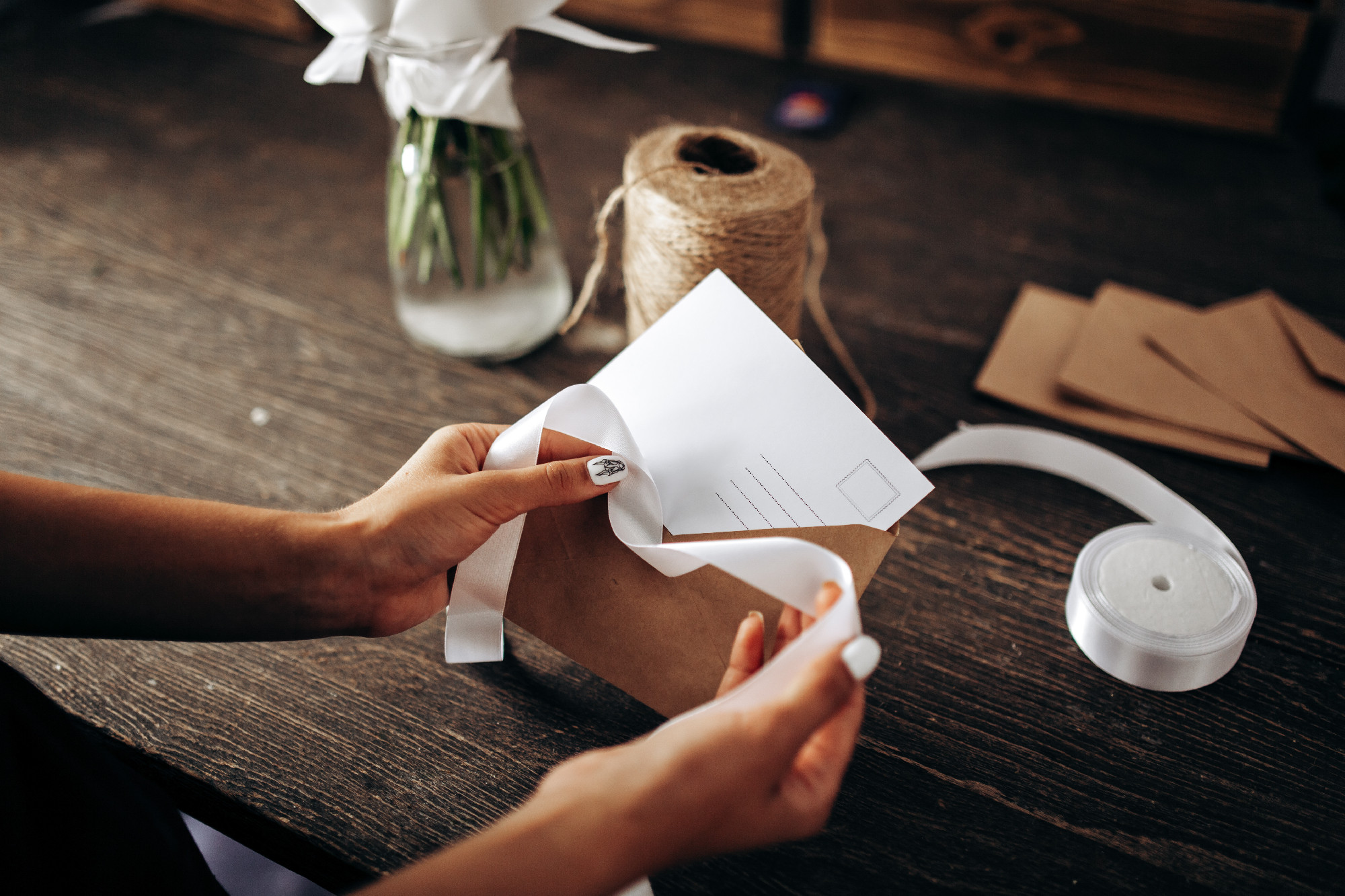 Florist is packing a postcard in an envelope with white ribbon o