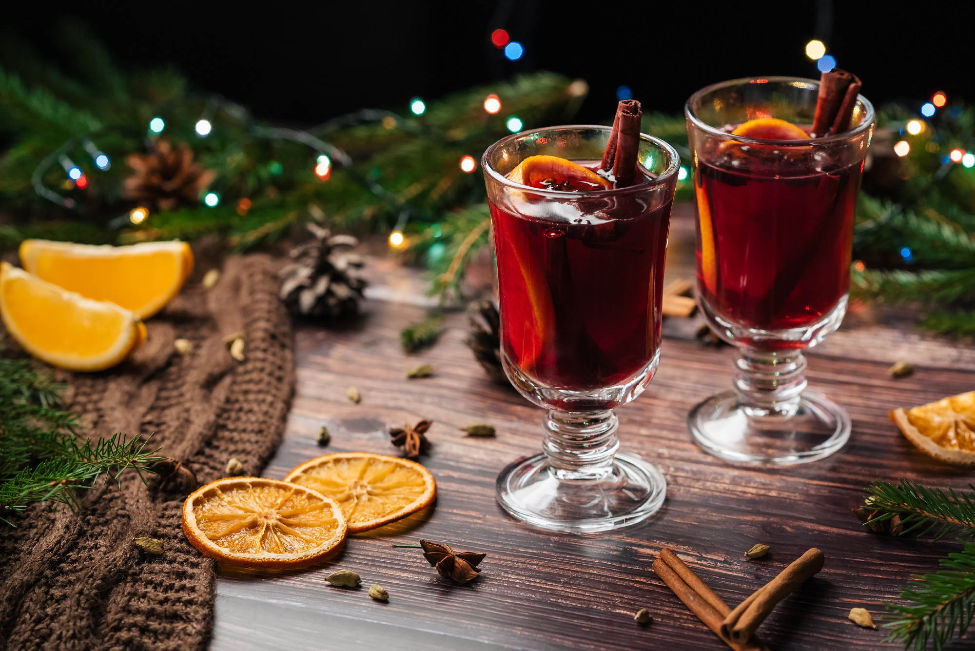 mulled wine in glass glasses with orange slices, cinnamon sticks and spices with Christmas decor