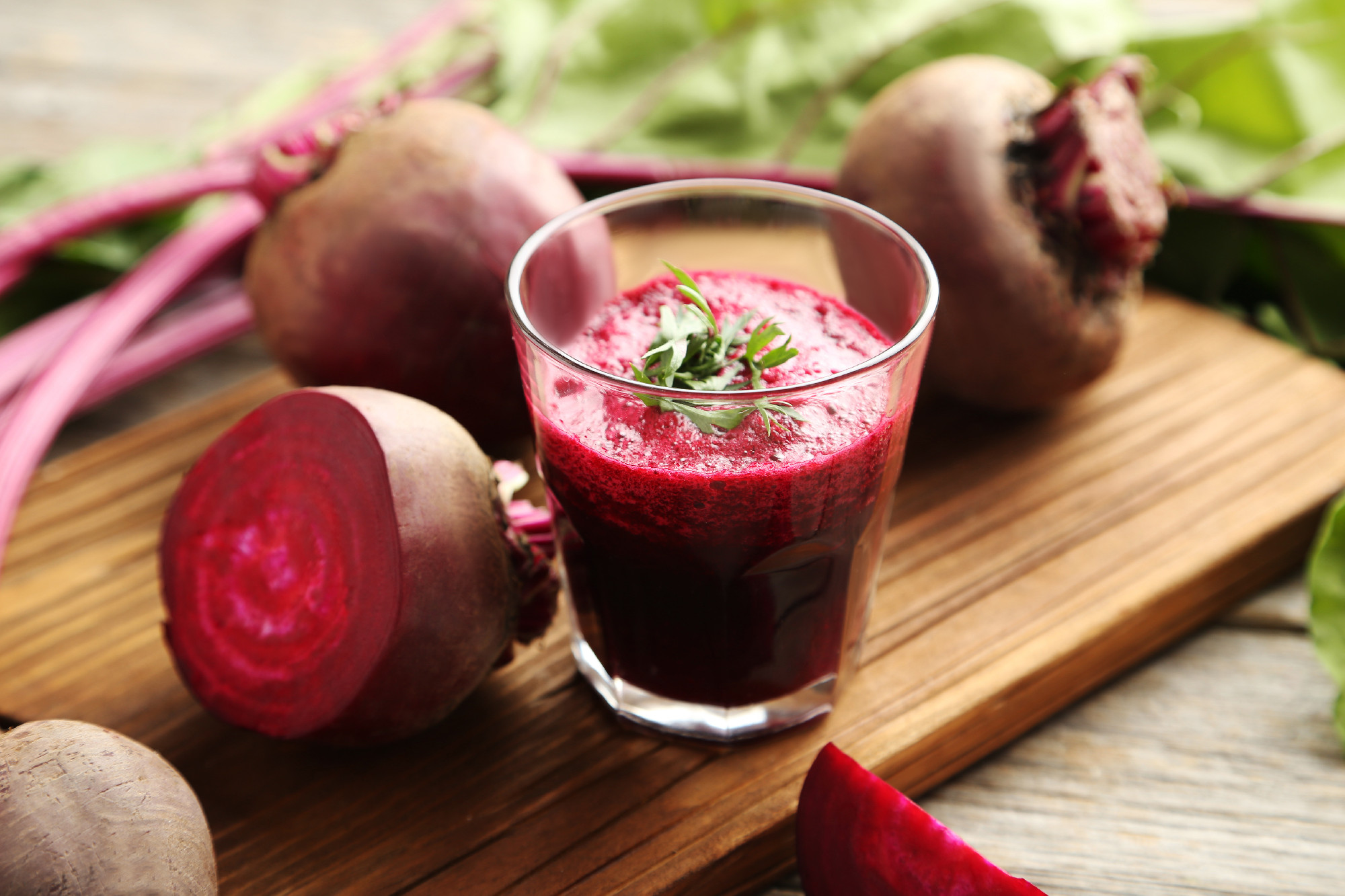 Fresh beets juice in glass on a grey wooden table