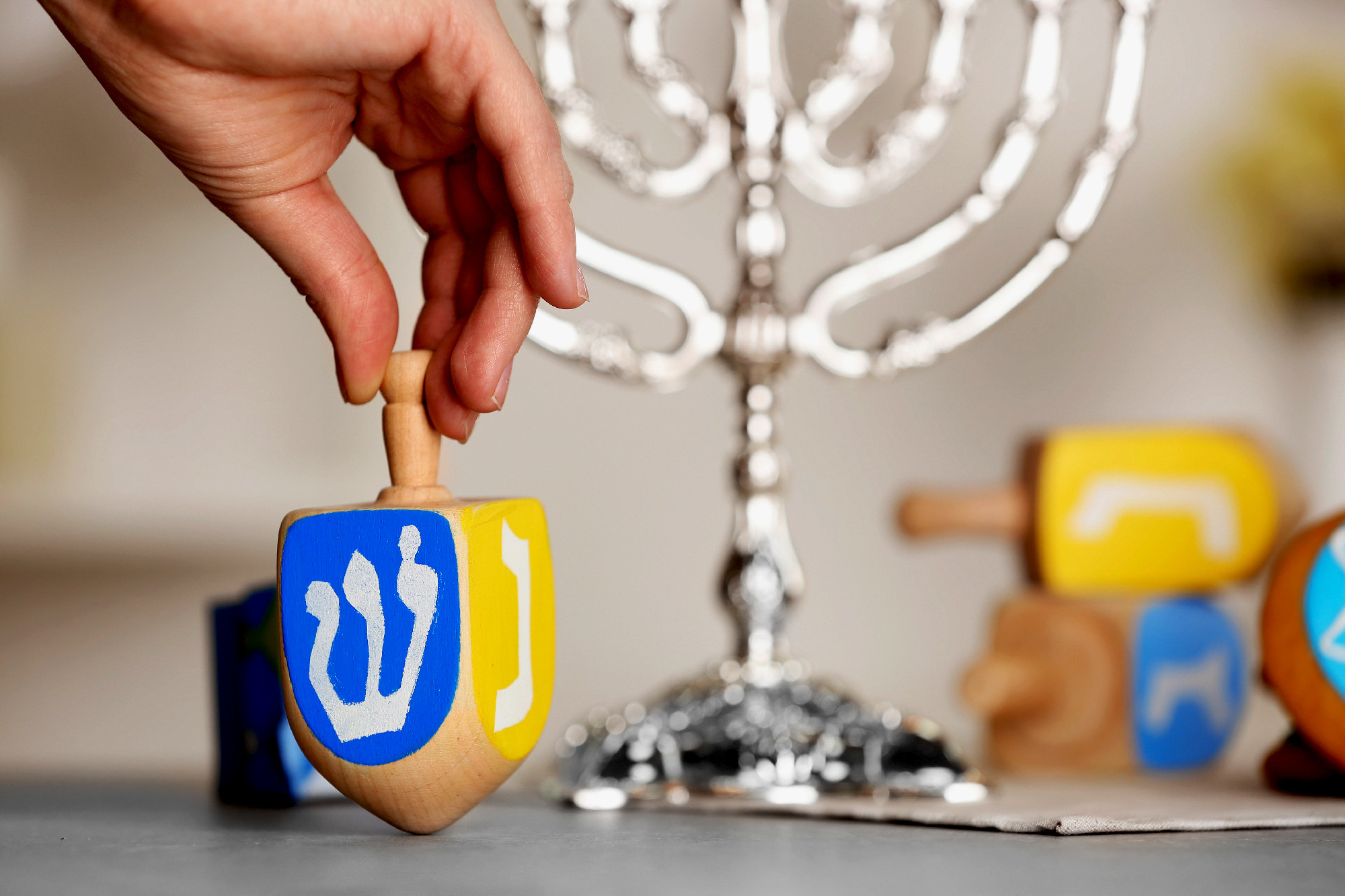 Female hand spinning wooden dreidel for Hanukkah on light table