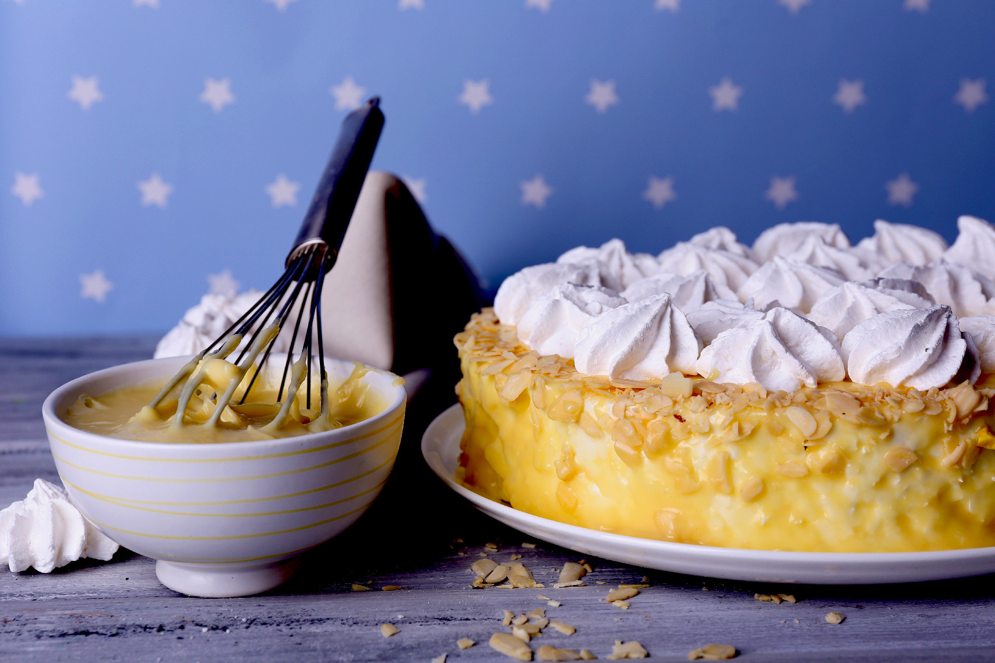 Tasty homemade meringue cake on wooden table, on blue background