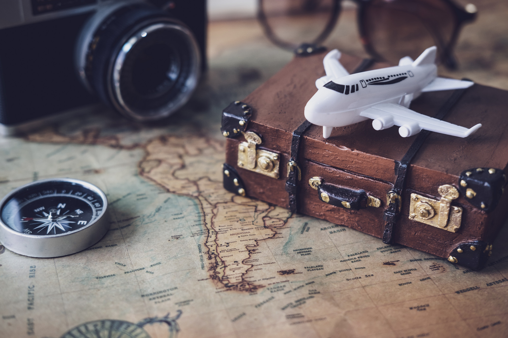 Toy plane and suitcase on vintage map with copy space, Travel co