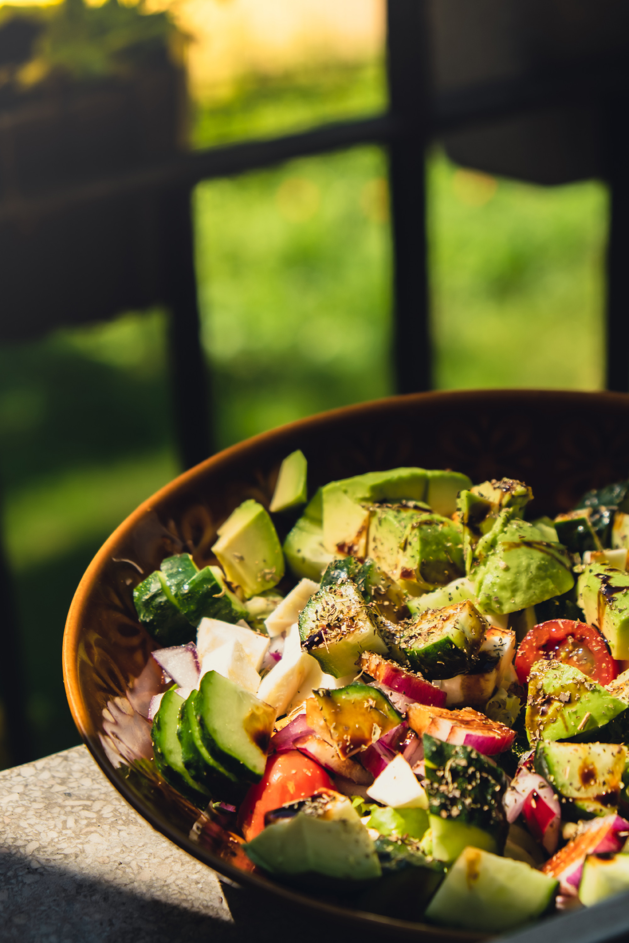 Avocado mix of vegetables salad in daytime outdoors. Fresh salad with tomatoes, avocado, lettuce onion cucumber. Healthy and detox food concept. Ketogenic diet