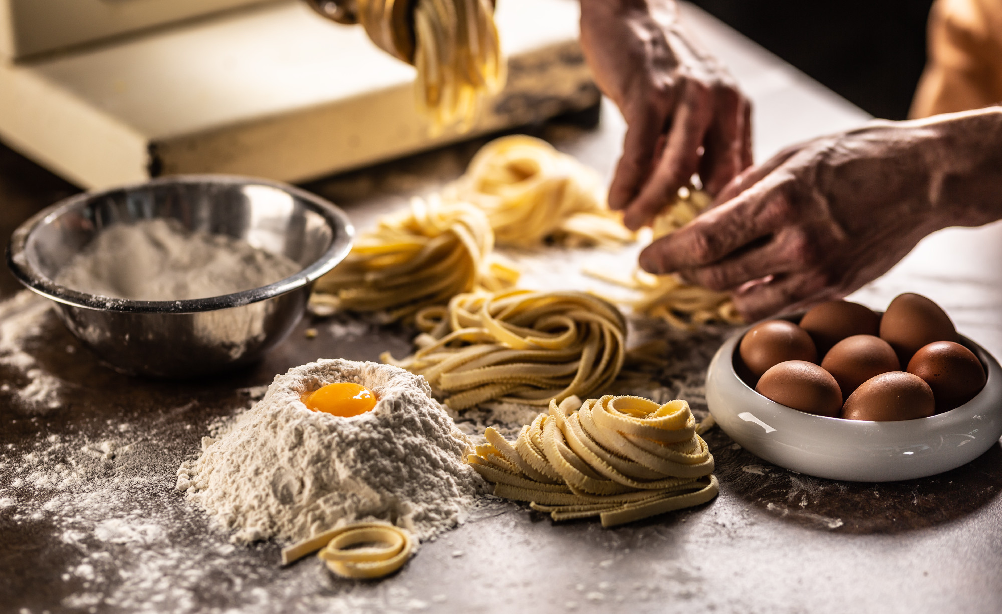 Hands of a chef twisting fettuccine pasta into nests after makin
