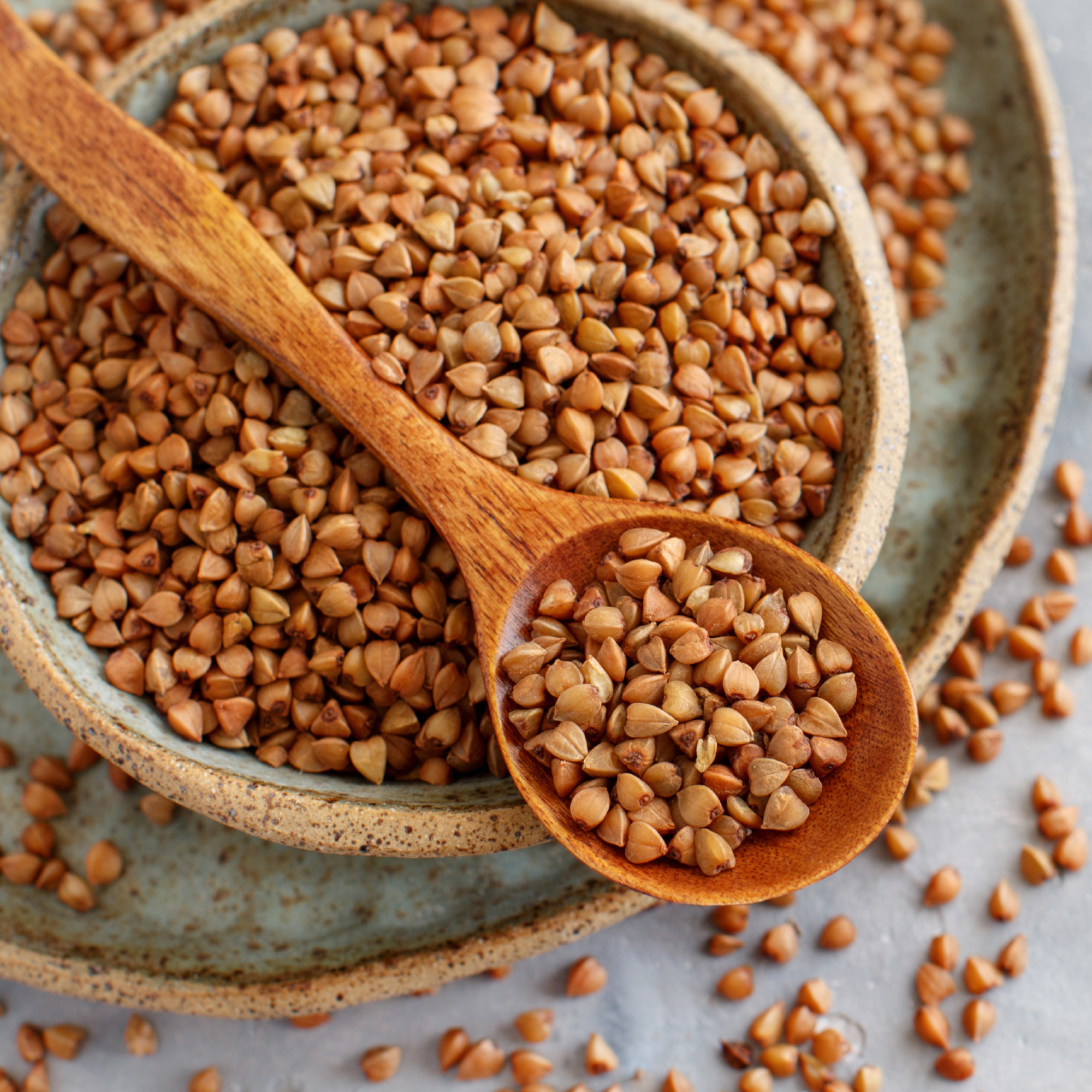 Raw dry buckwheat grain in a bowl with a spoon