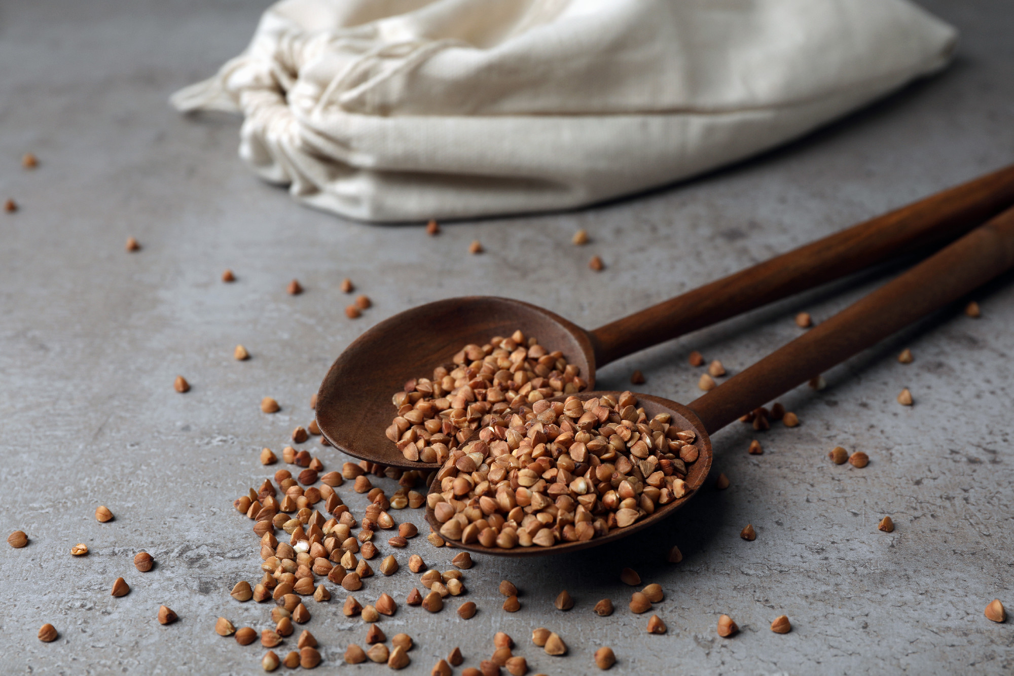 Spoons with uncooked buckwheat on table. Organic wholesome product�
