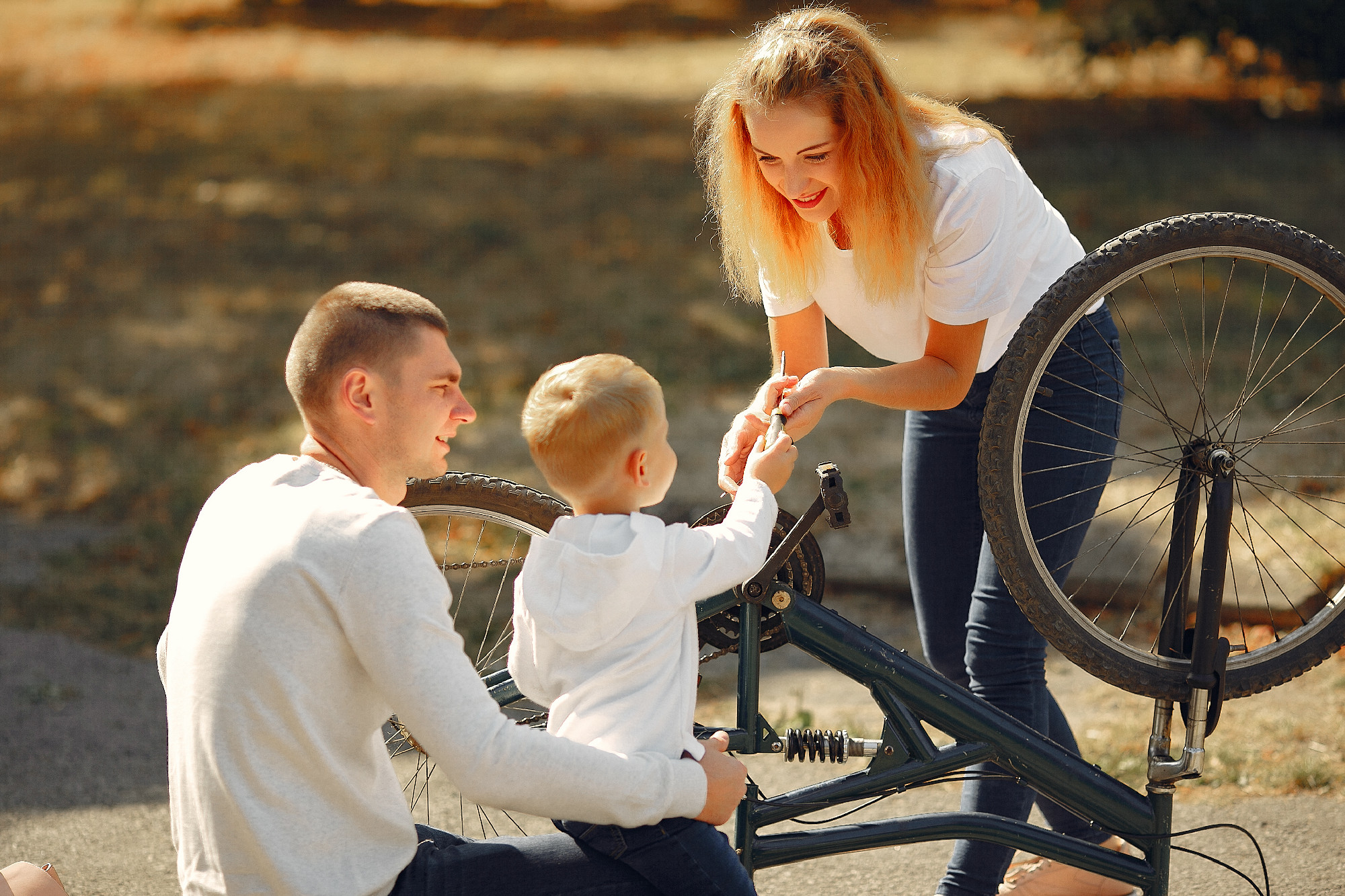 Family with son repare the bike in a park