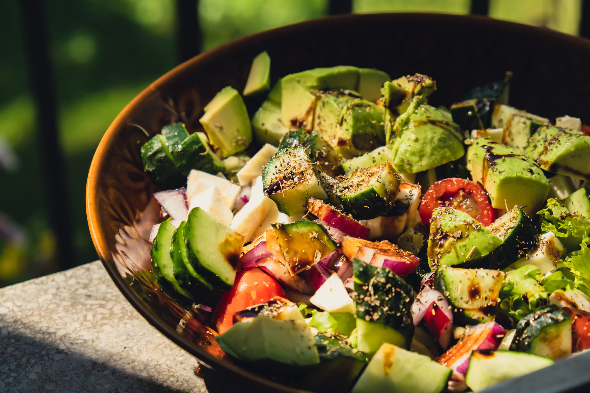 Avocado mix of vegetables salad in daytime outdoors. Fresh salad with tomatoes, avocado, lettuce onion cucumber. Healthy and detox food concept. Ketogenic diet