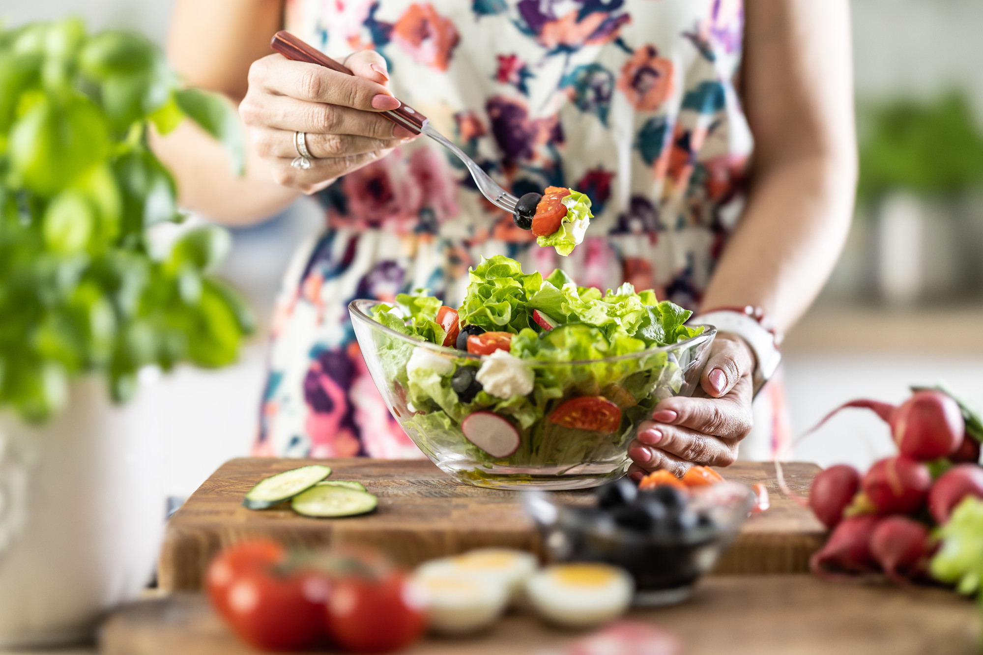 A portion of healthy salad on a fork in the hand of a young woma
