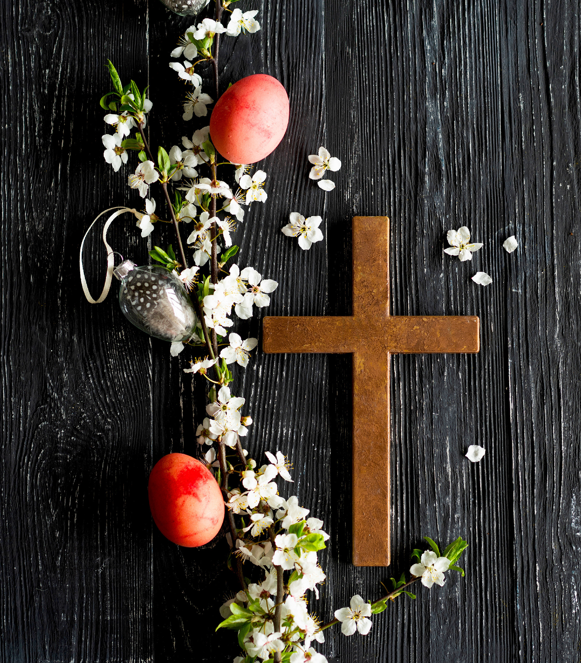 Spring cherry blossoms and Easter eggs and cross on old wooden b