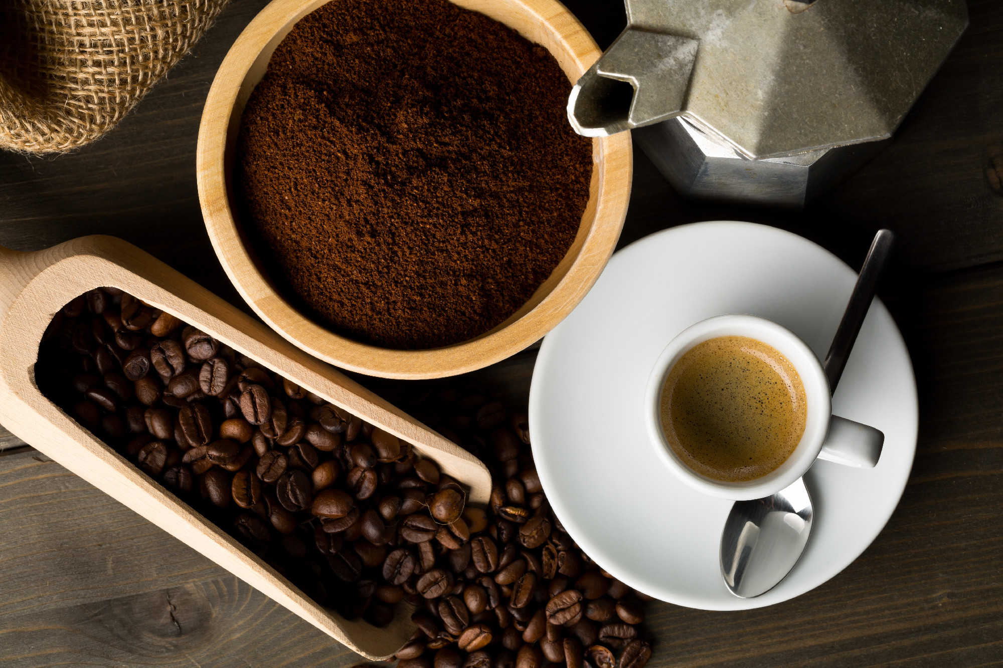 Coffee beans, ground coffee powder and cup of espresso with stov