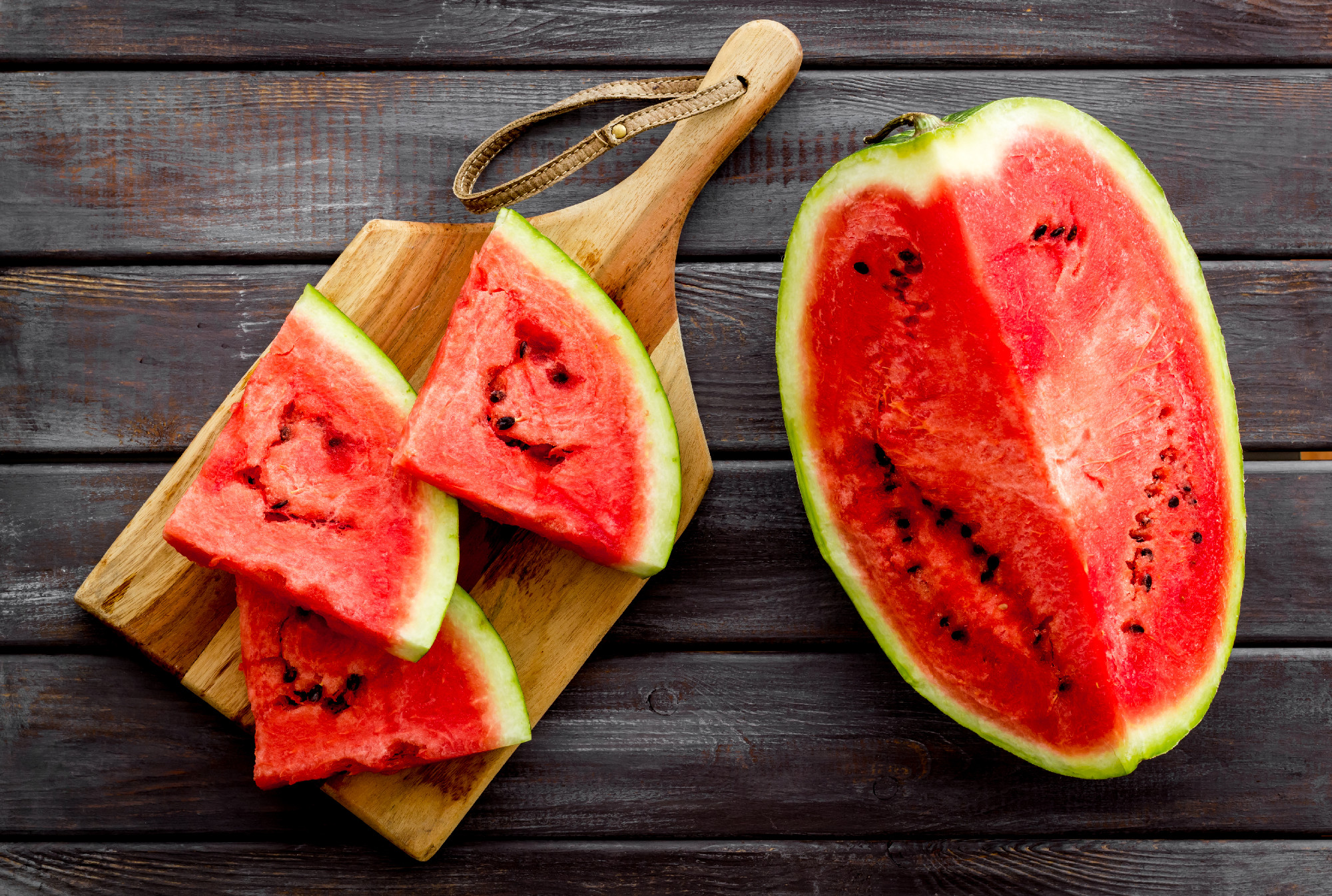 Cut watermelon for break with fruit on wooden background top view