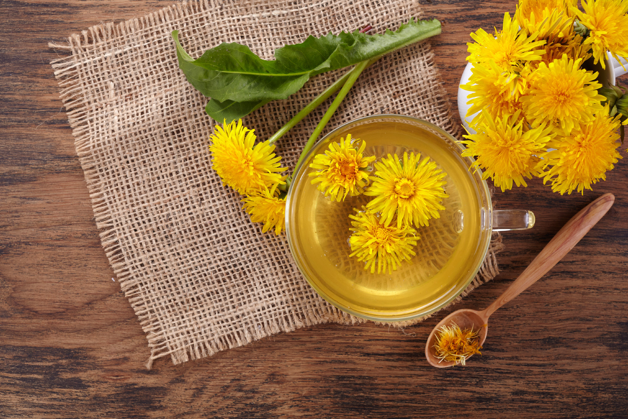 Cup ph healthy dandelion tea on vintage wooden background. Fresh herbs.