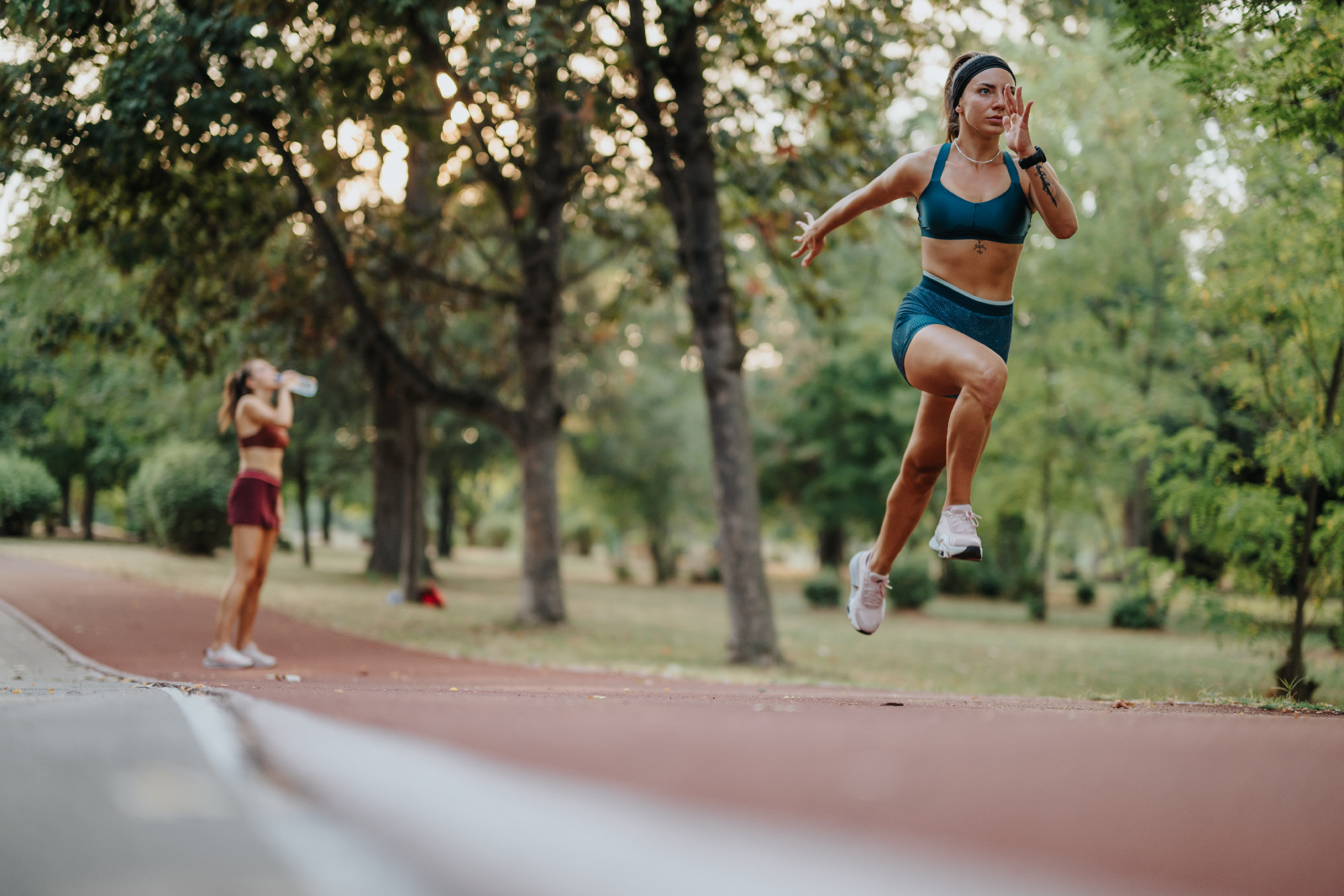 Fit athletes with athletic bodies jog outdoors in a green park. Their determination and motivation are seen as they work towards their fitness goals.