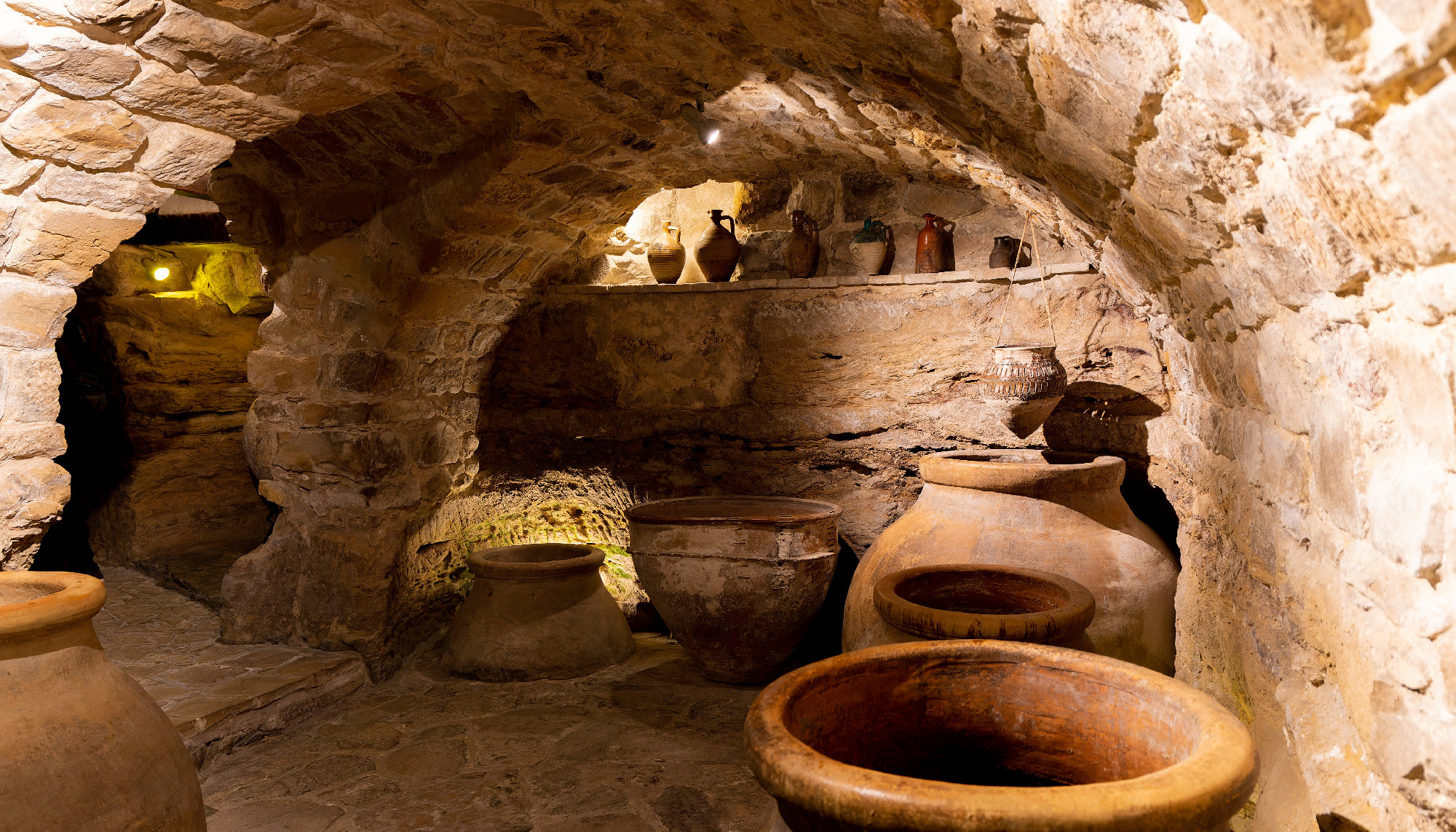 A room with a lot of vases and a stone ceiling