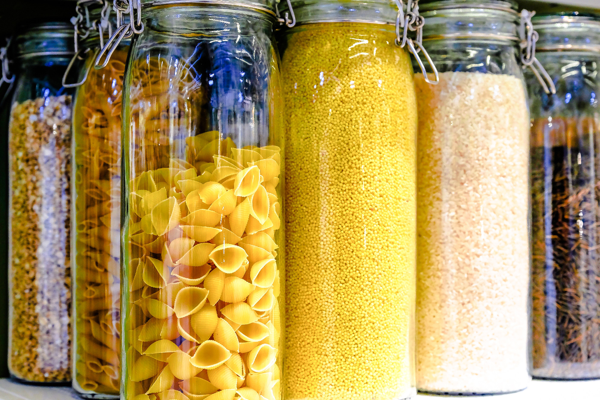 Various raw cereals, grains, beans and pasta for healthy cooking in glass jars on the kitchen shelf.Clean food, vegetarian, vegan, balanced diet concept