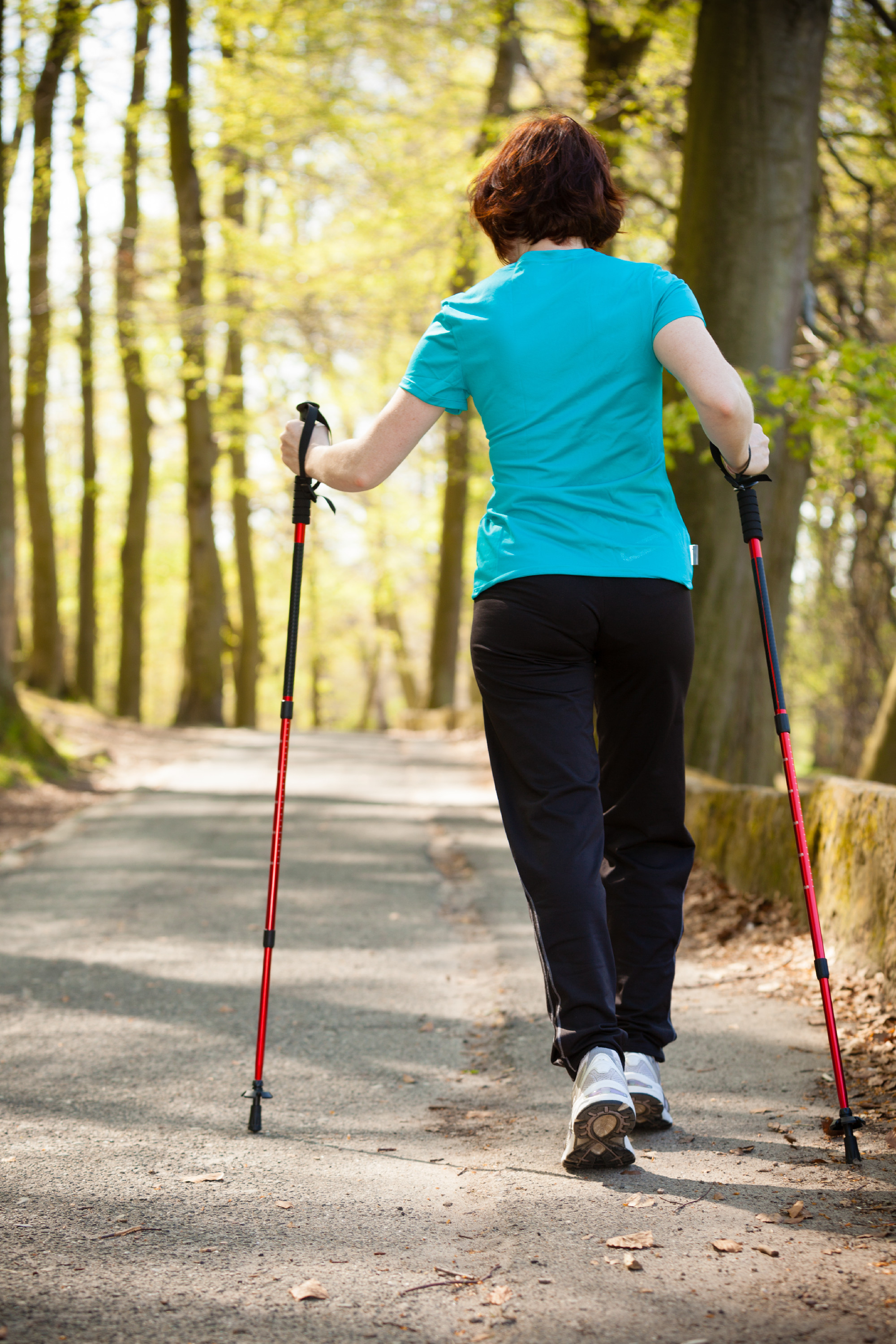 Nordic walking. Woman hiking in the forest park.