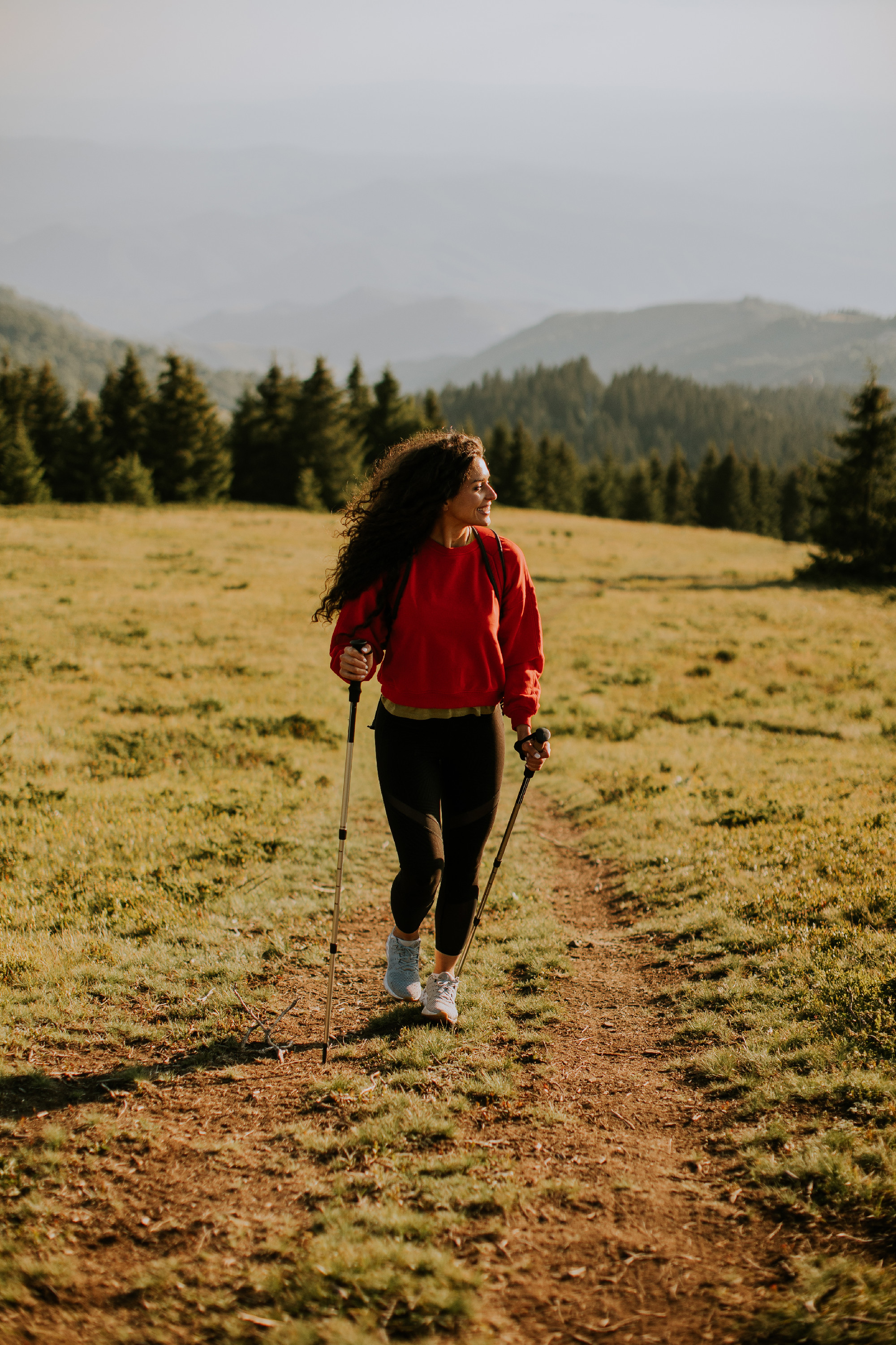 Young woman walking with backpack over green hills