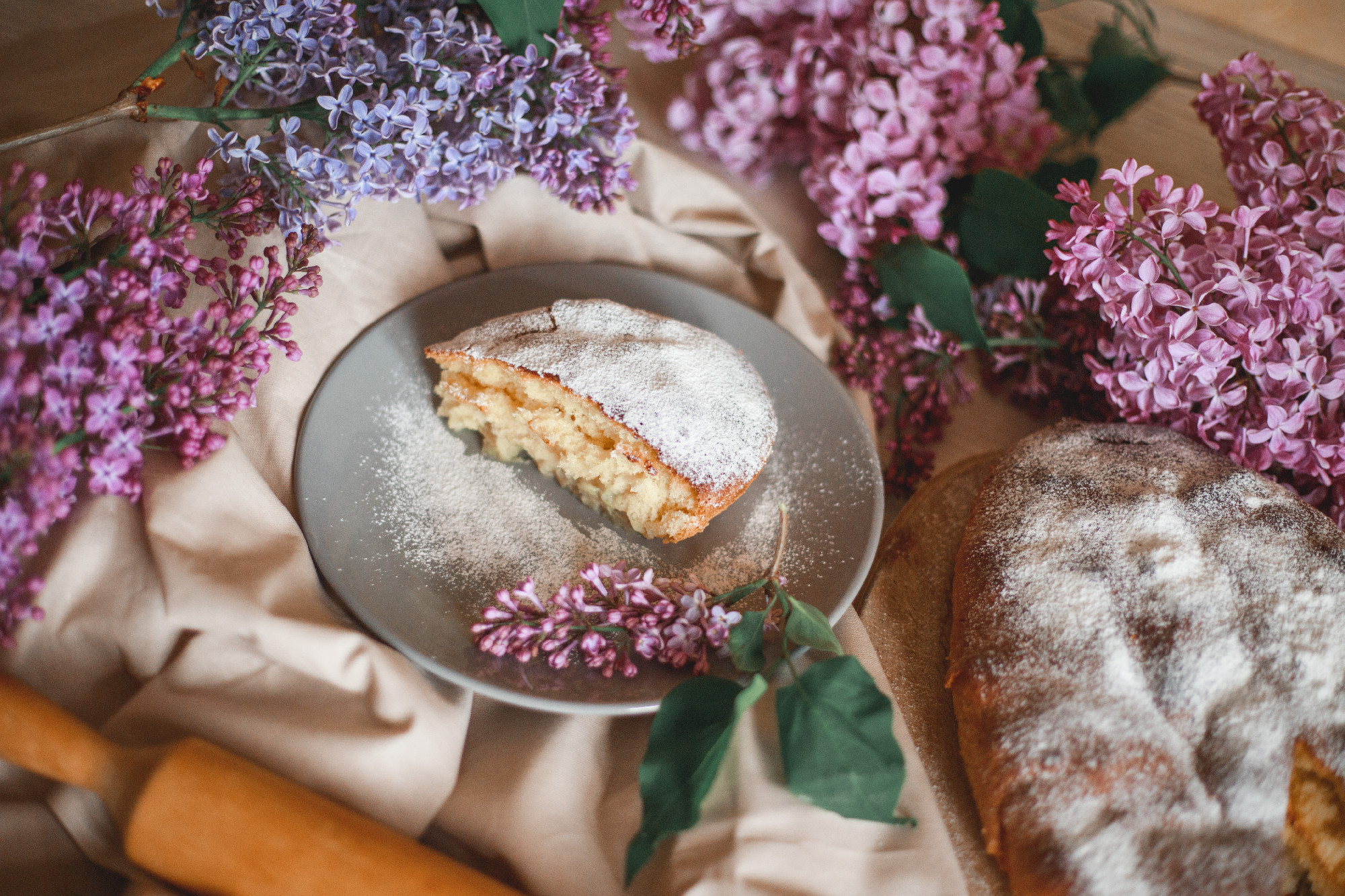 Homemade Apple pie on a wooden table next to a bowl of lilacs. Gentle toning.