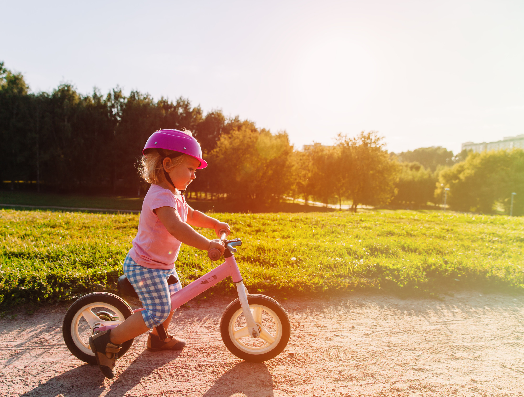 little girl with helmet riding bike at sunset