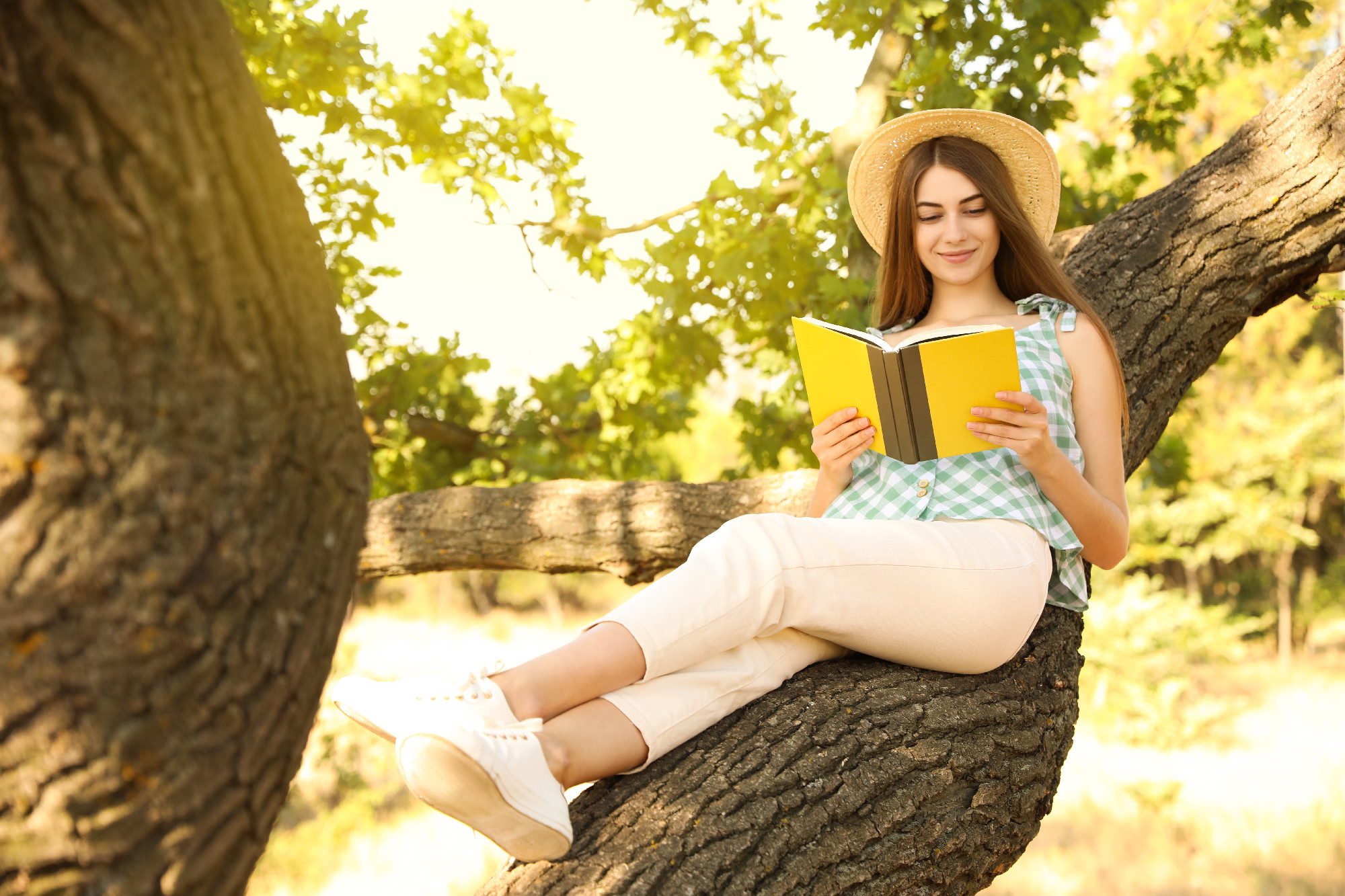 Young woman reading book on tree in park
