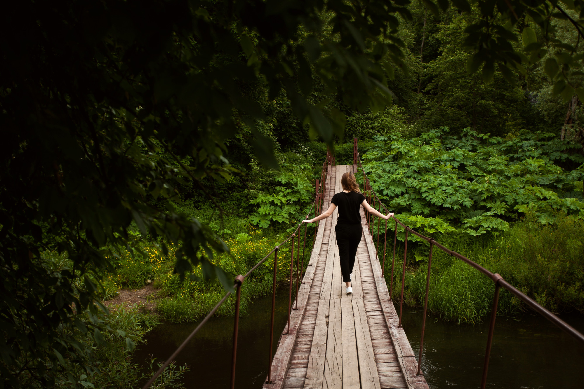 female walking on suspension bridge from back