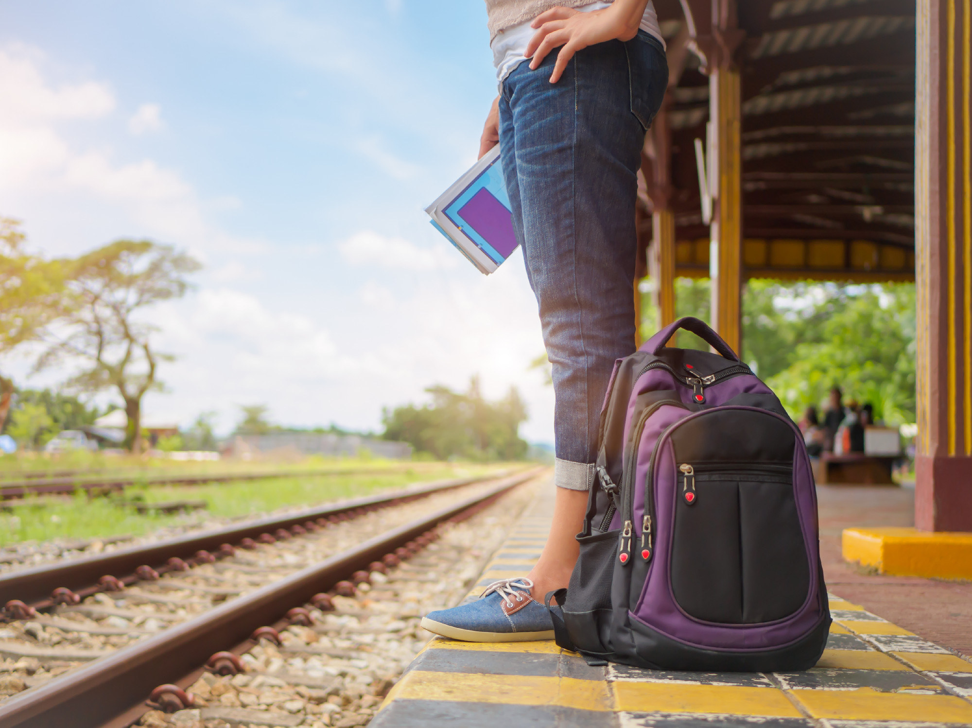 Traveler woman walking and waits train on the railway platform.