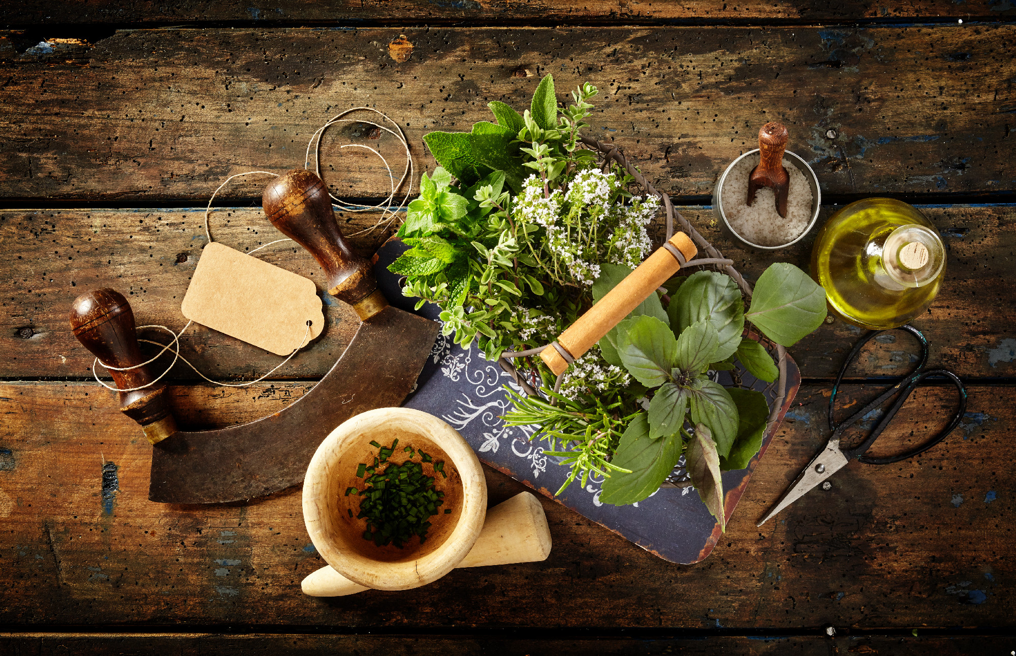 Herbs, scissors and mezzaluna over rustic table