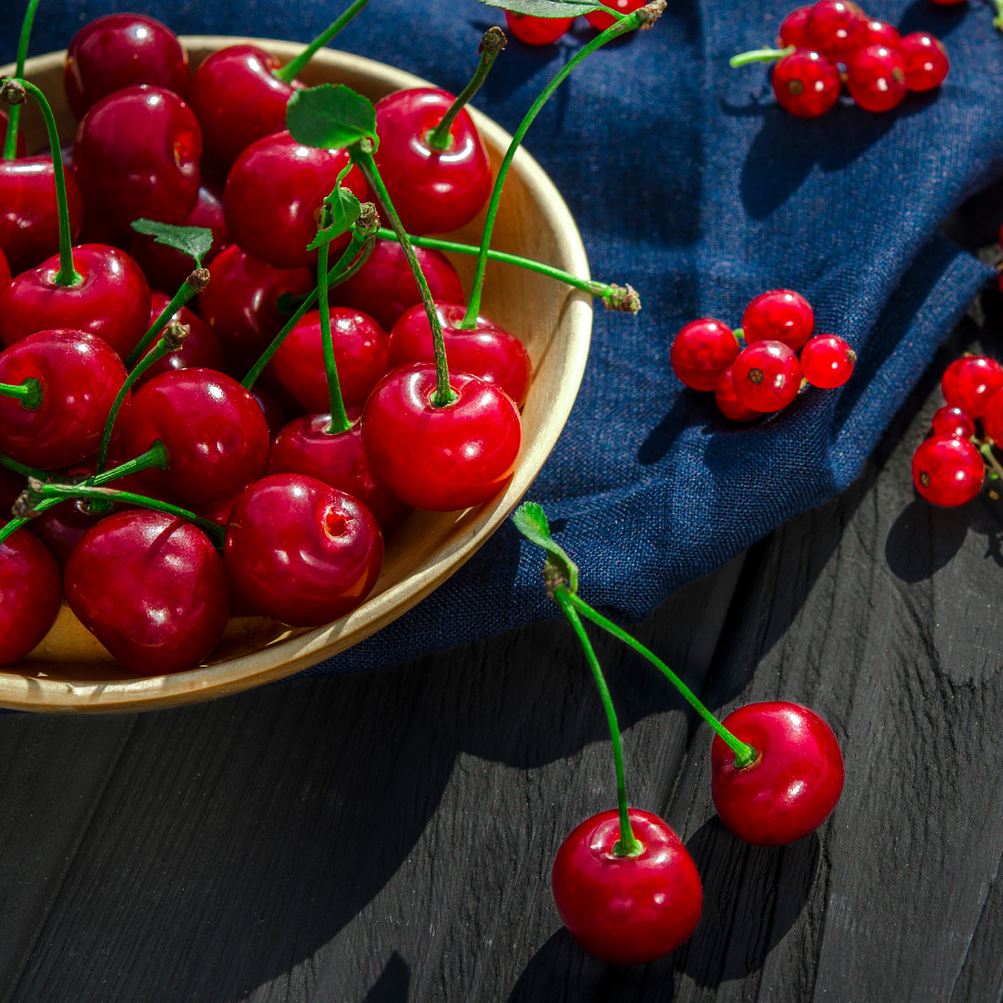 Red cherry and currants lie on a black wood background