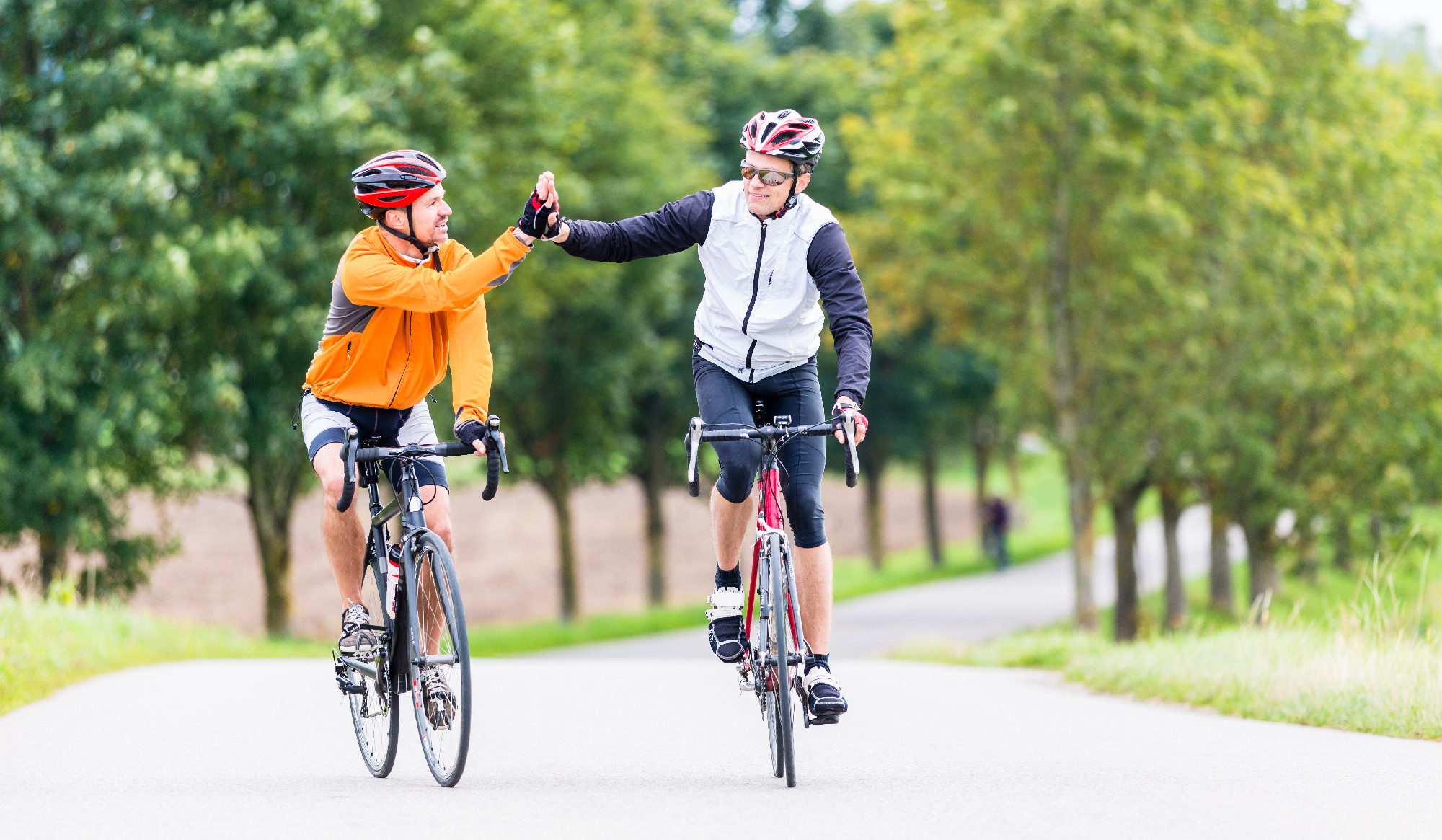 Racing cyclists after sport and giving high five