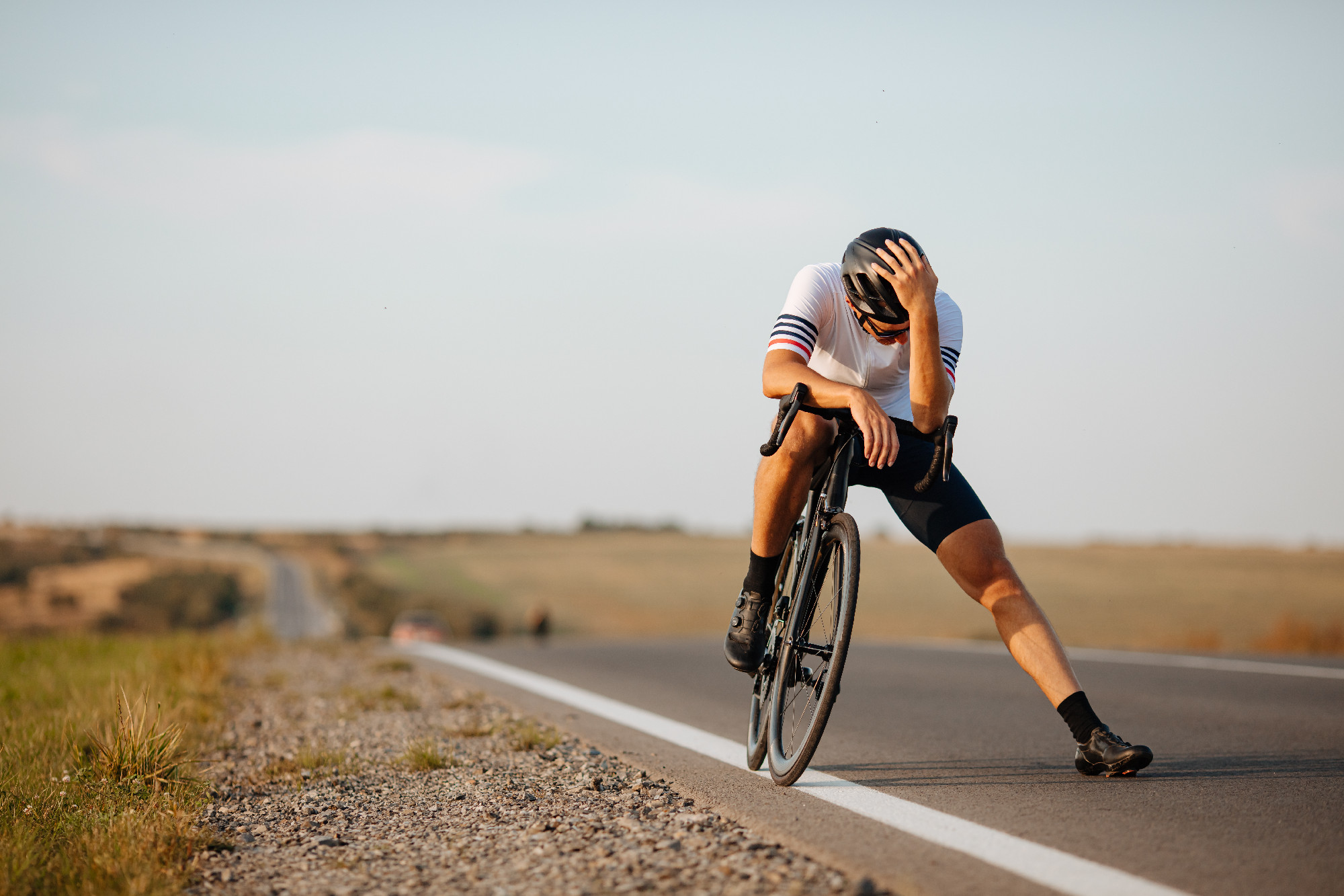 Exhausted cyclist relaxing on road after long riding